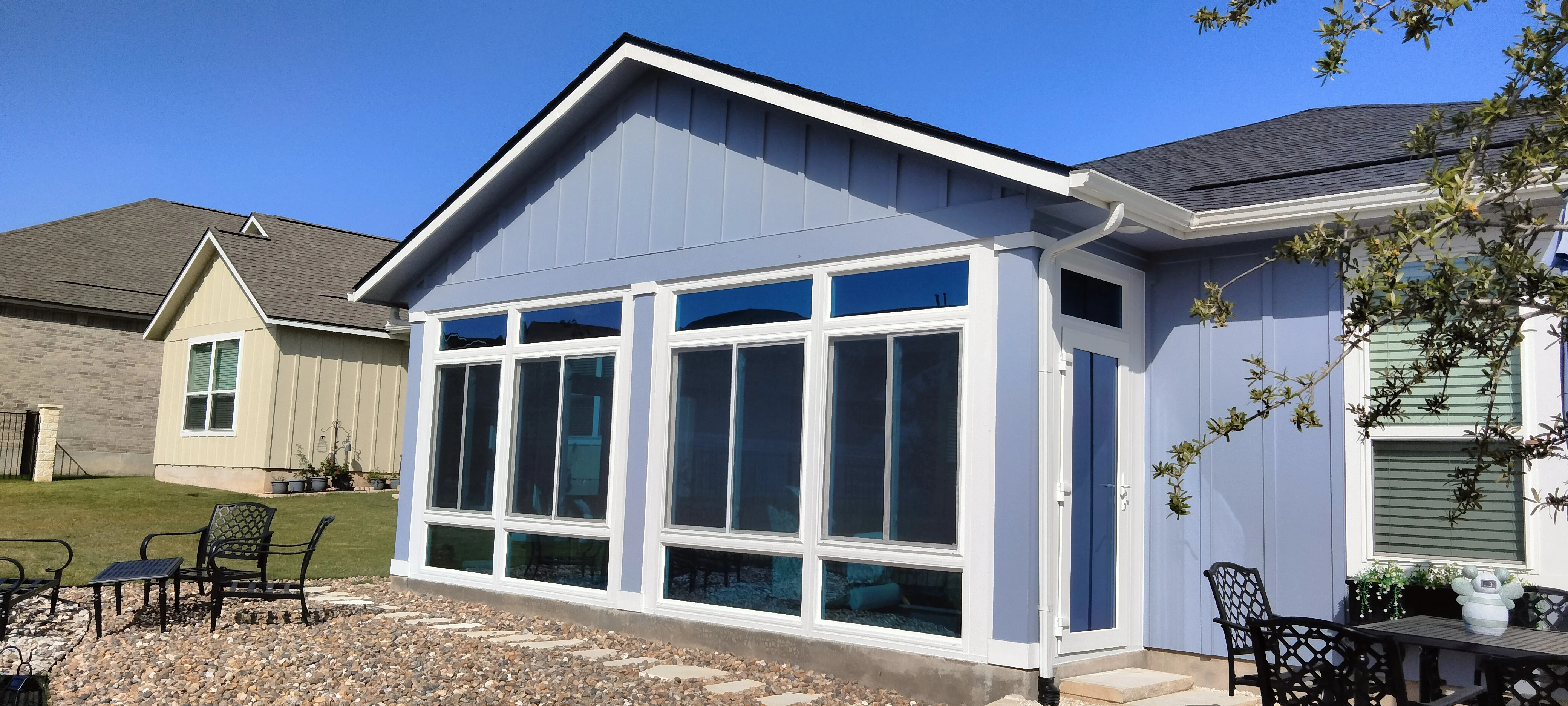 White aluminum patio enclosure with glass panels and transom windows, peaked roof design