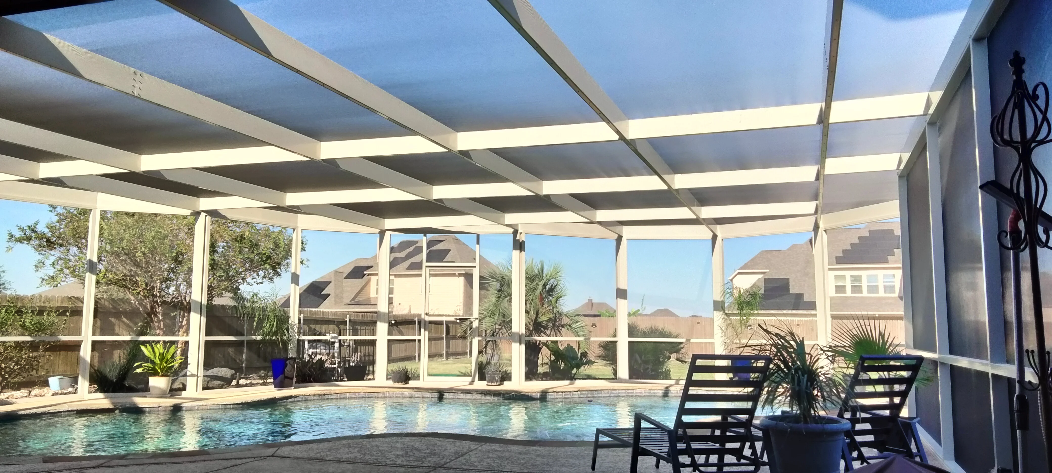 Motorized patio enclosure with retractable screens over residential pool, aluminum frame construction