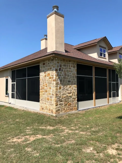 Stone knee wall patio enclosure with black aluminum frame and glass panels
