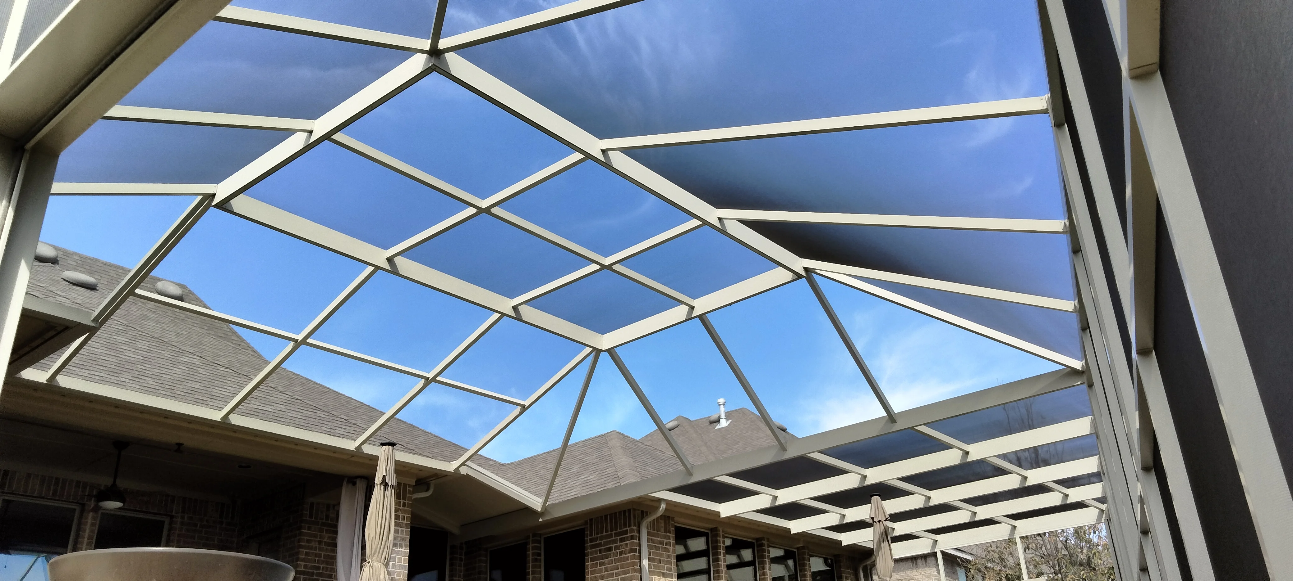 Polycarbonate patio roof with white aluminum frame and geometric panel design