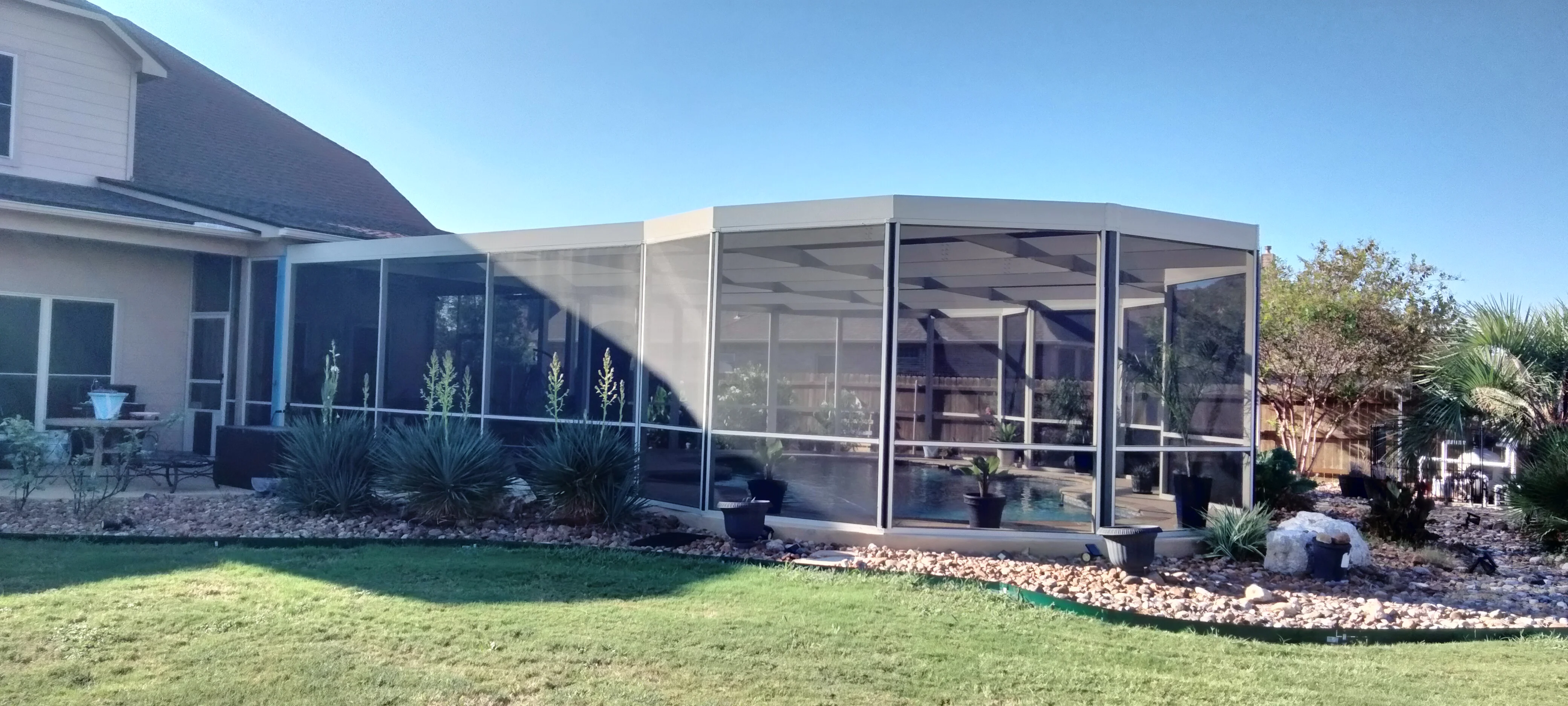 Aluminum patio enclosure with screened panels and solid roof attached to residential home