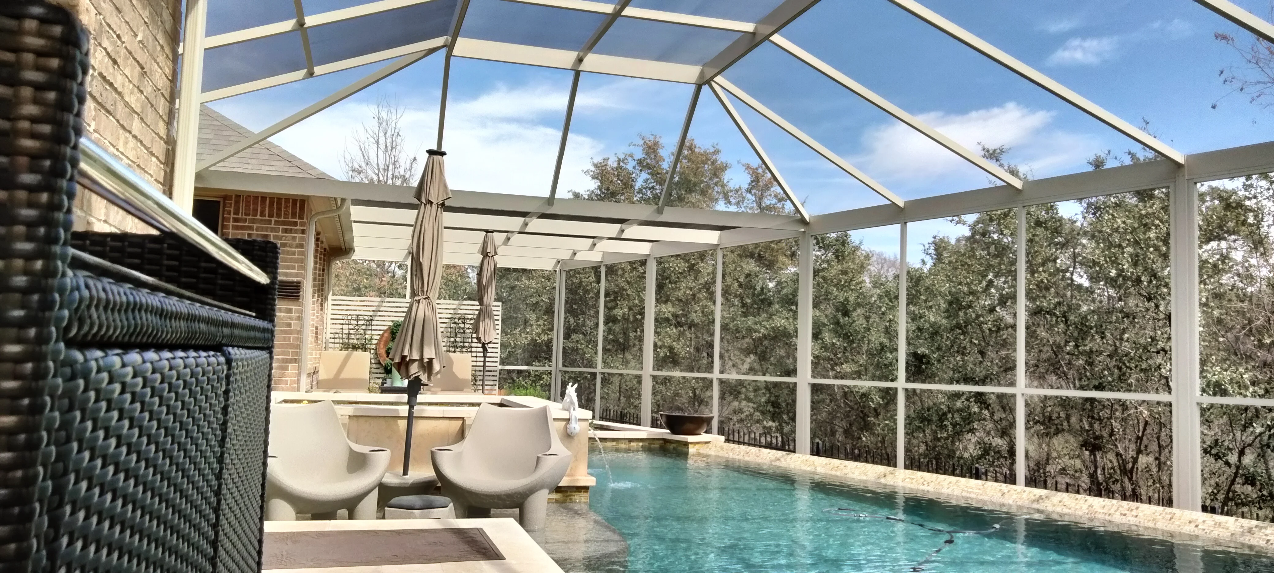 Aluminum pool enclosure with retractable roof, screen panels, and travertine deck