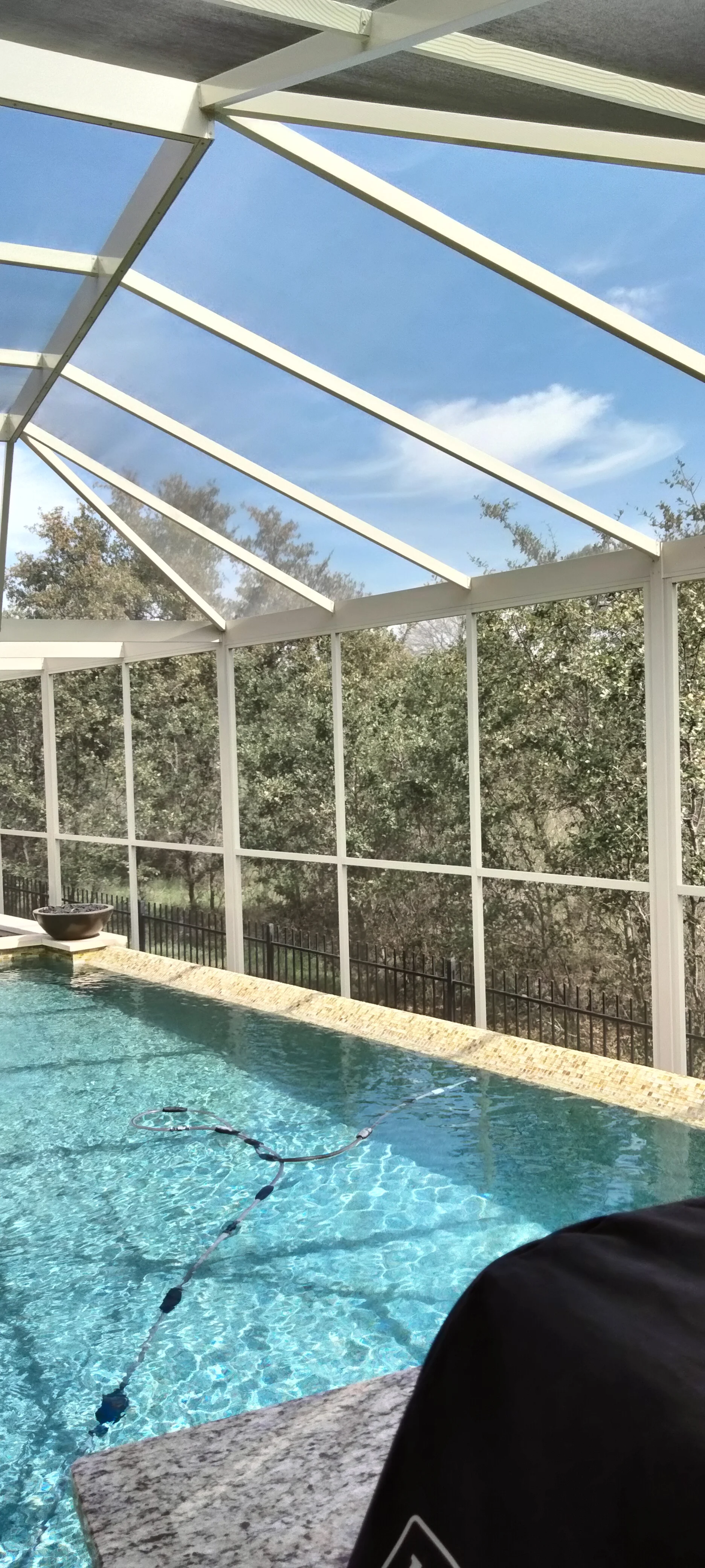 Aluminum and glass pool enclosure with angled roof panels and full-height glass walls