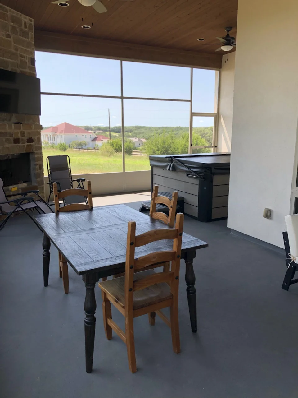 Glass patio enclosure with aluminum frame, knee wall, concrete floor, and brick fireplace
