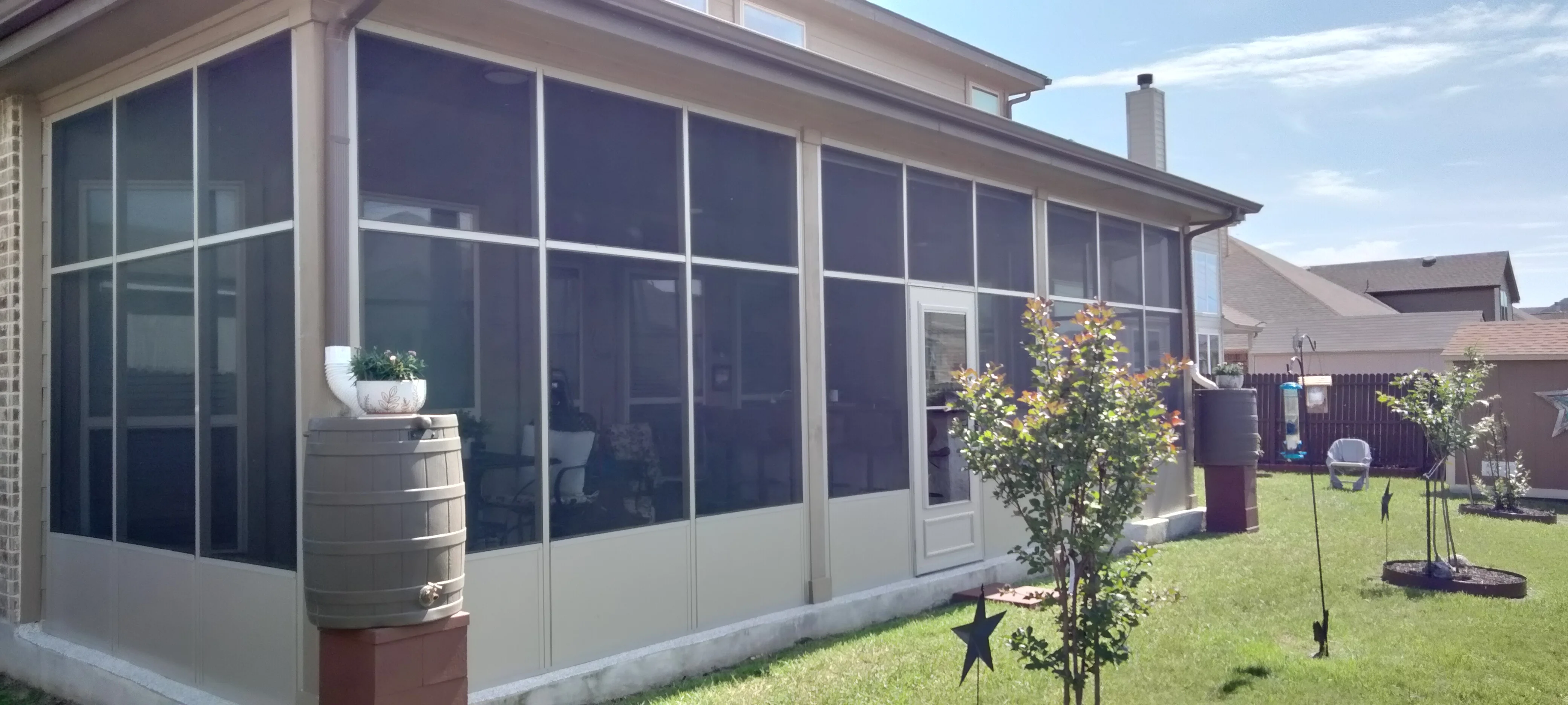 Aluminum-framed screened patio with dark mesh panels and white base, sliding glass door, and concrete foundation