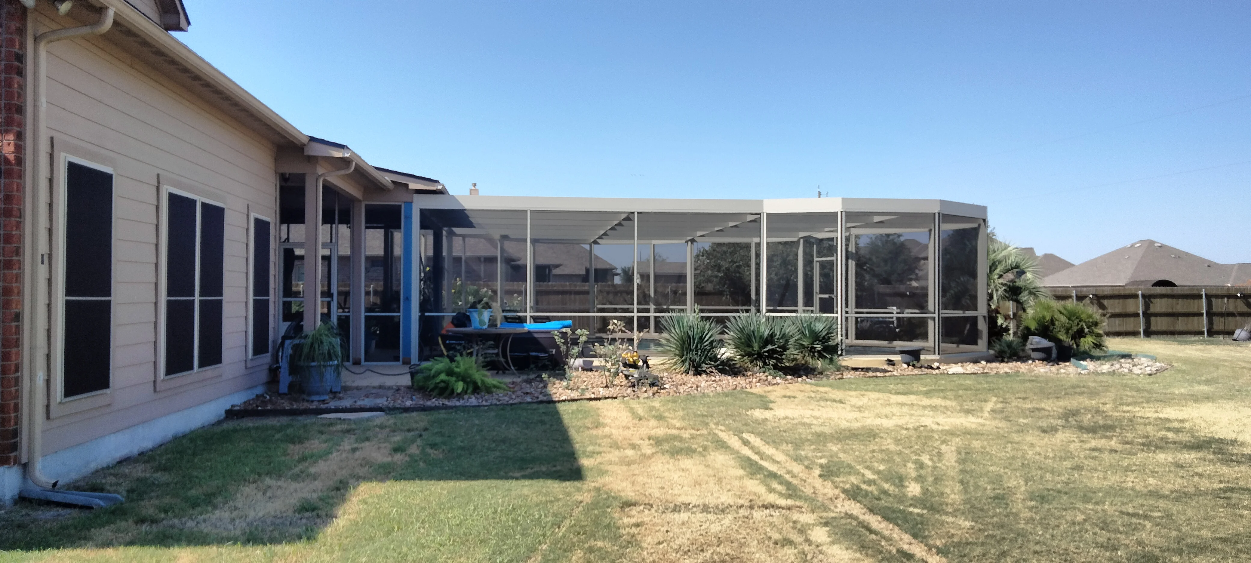 Aluminum frame patio enclosure with screening and glass panels on residential home