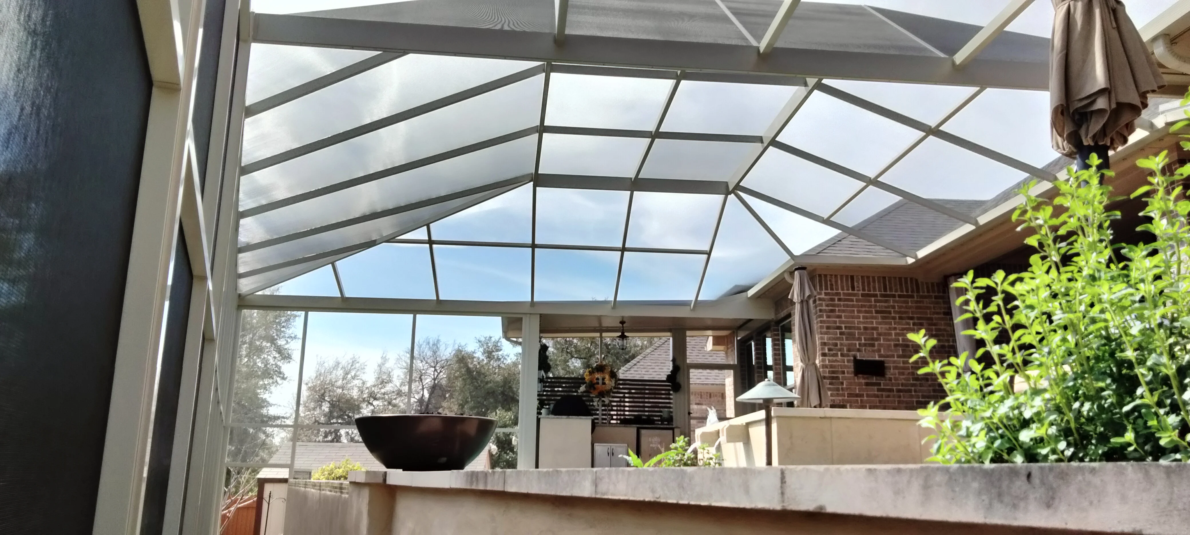 Polycarbonate patio roof with aluminum frame over outdoor kitchen and brick home
