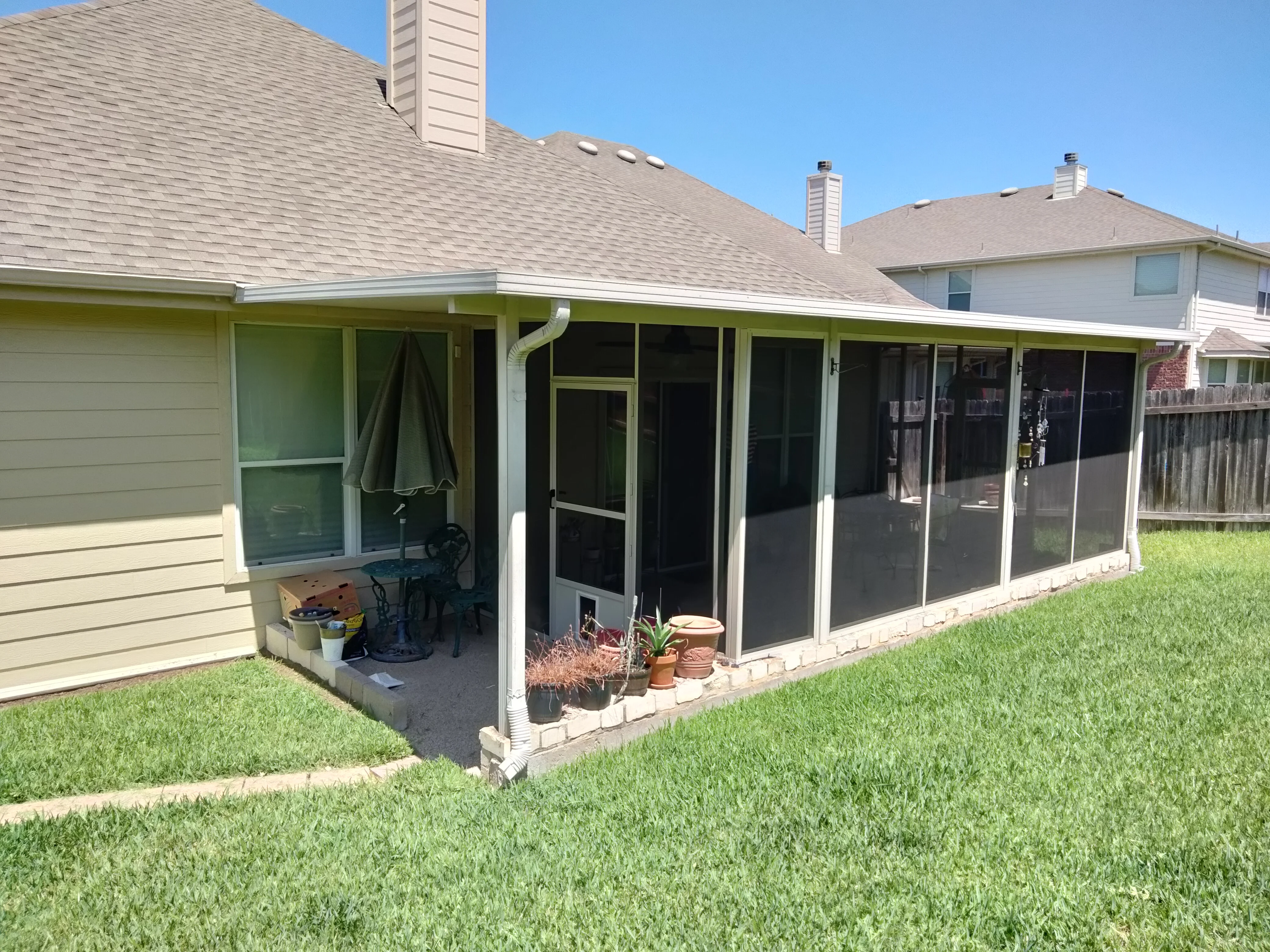 White aluminum screened patio with full-length screens and brick foundation attached to residential home