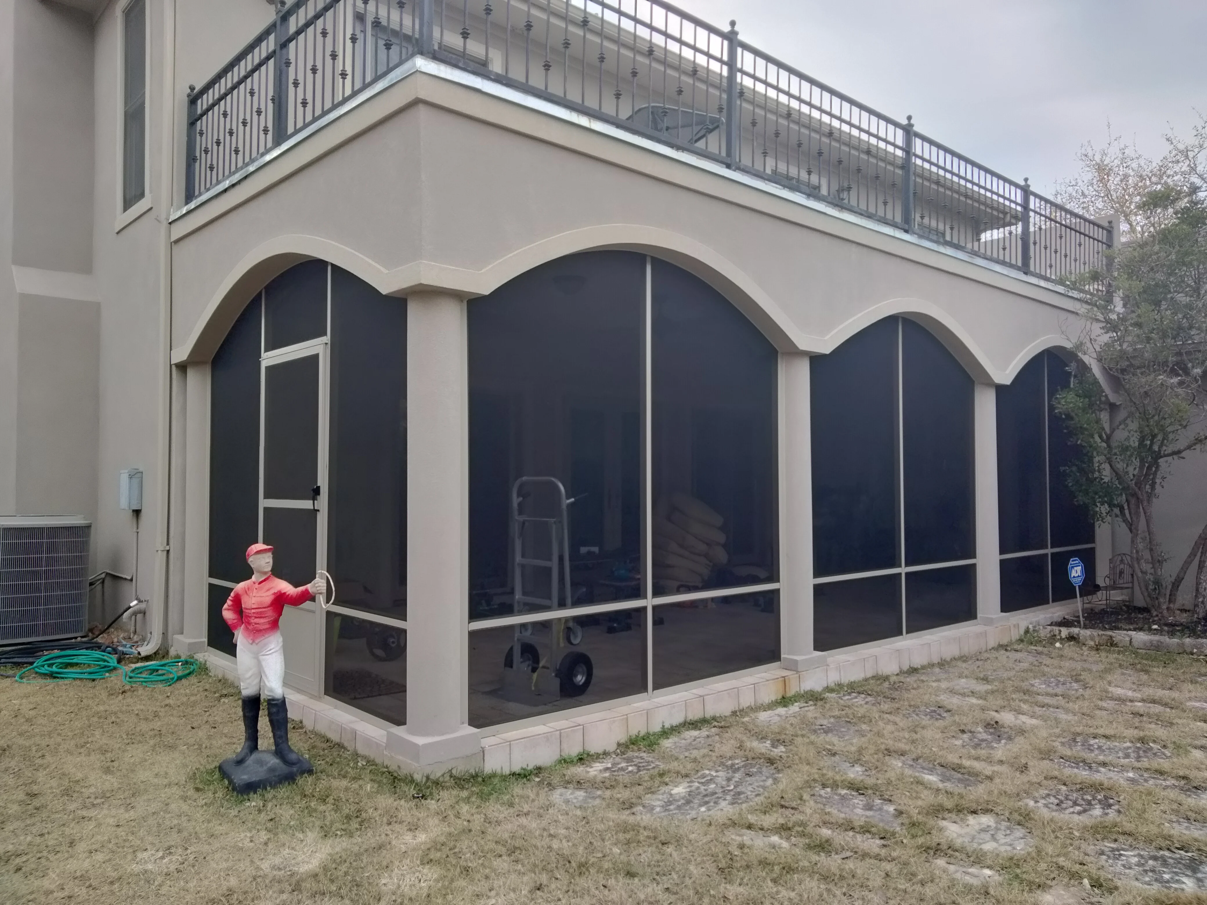 White arched patio enclosure with dark mesh screens and curved soffit detail