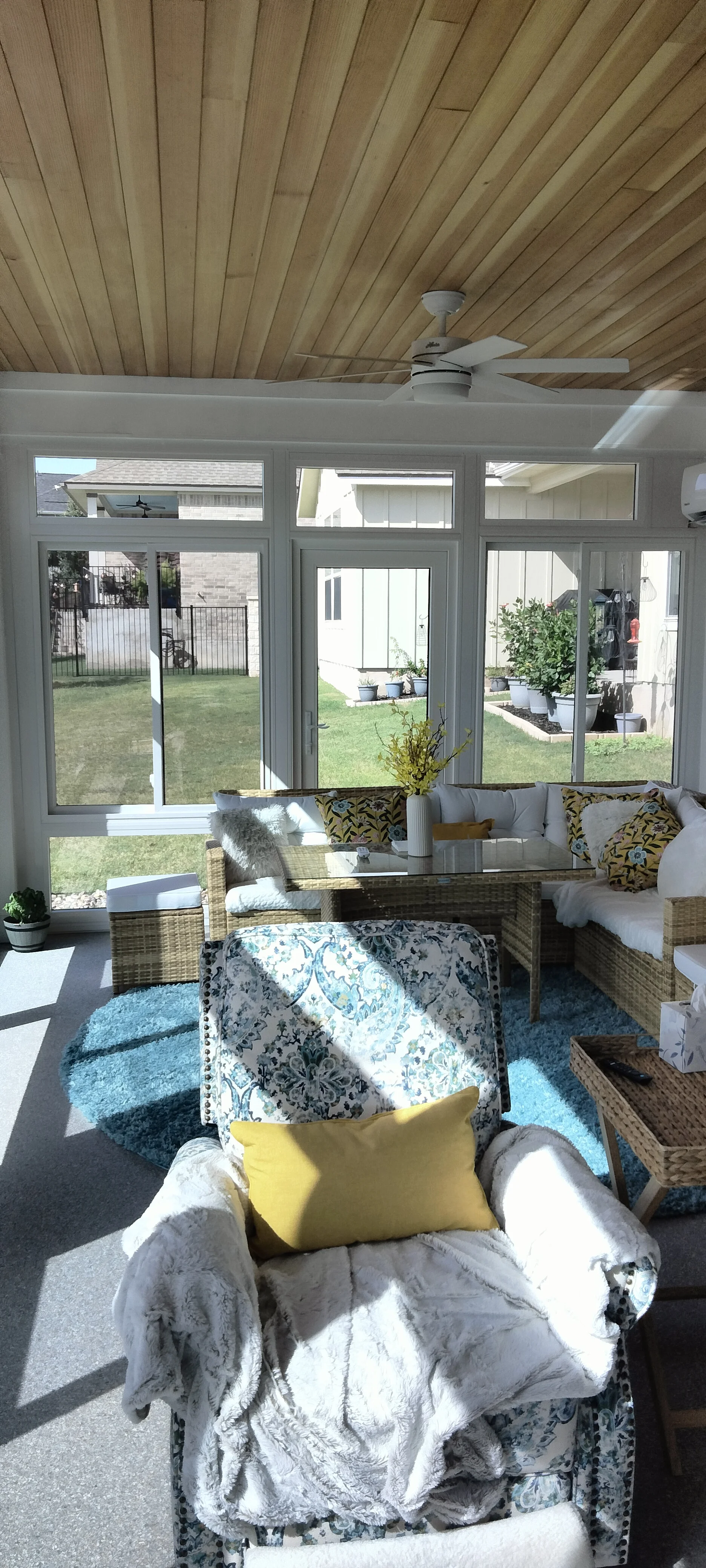 Screened patio with glass doors, shiplap ceiling, wicker furniture, and backyard views