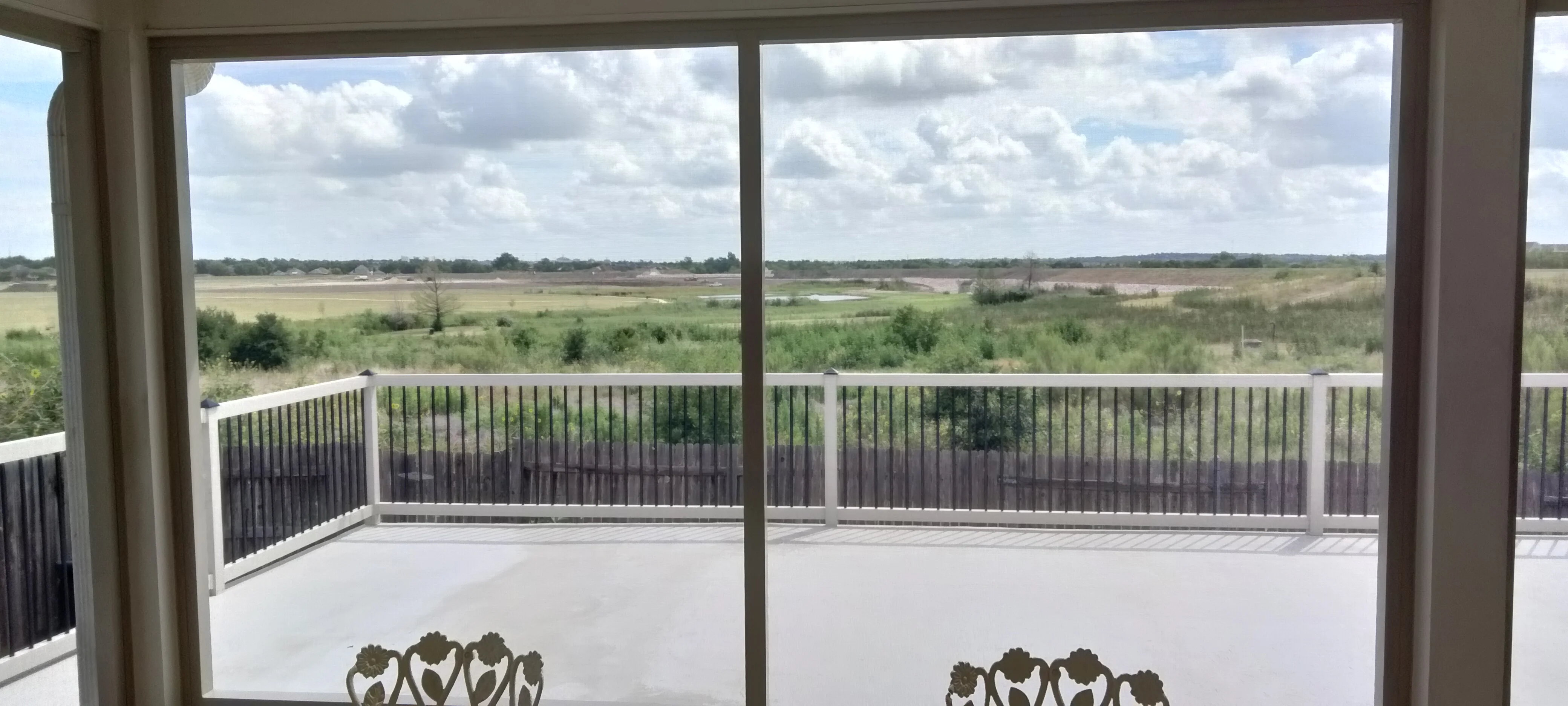 Elevated composite deck with white aluminum railings and vertical balusters overlooking rural landscape