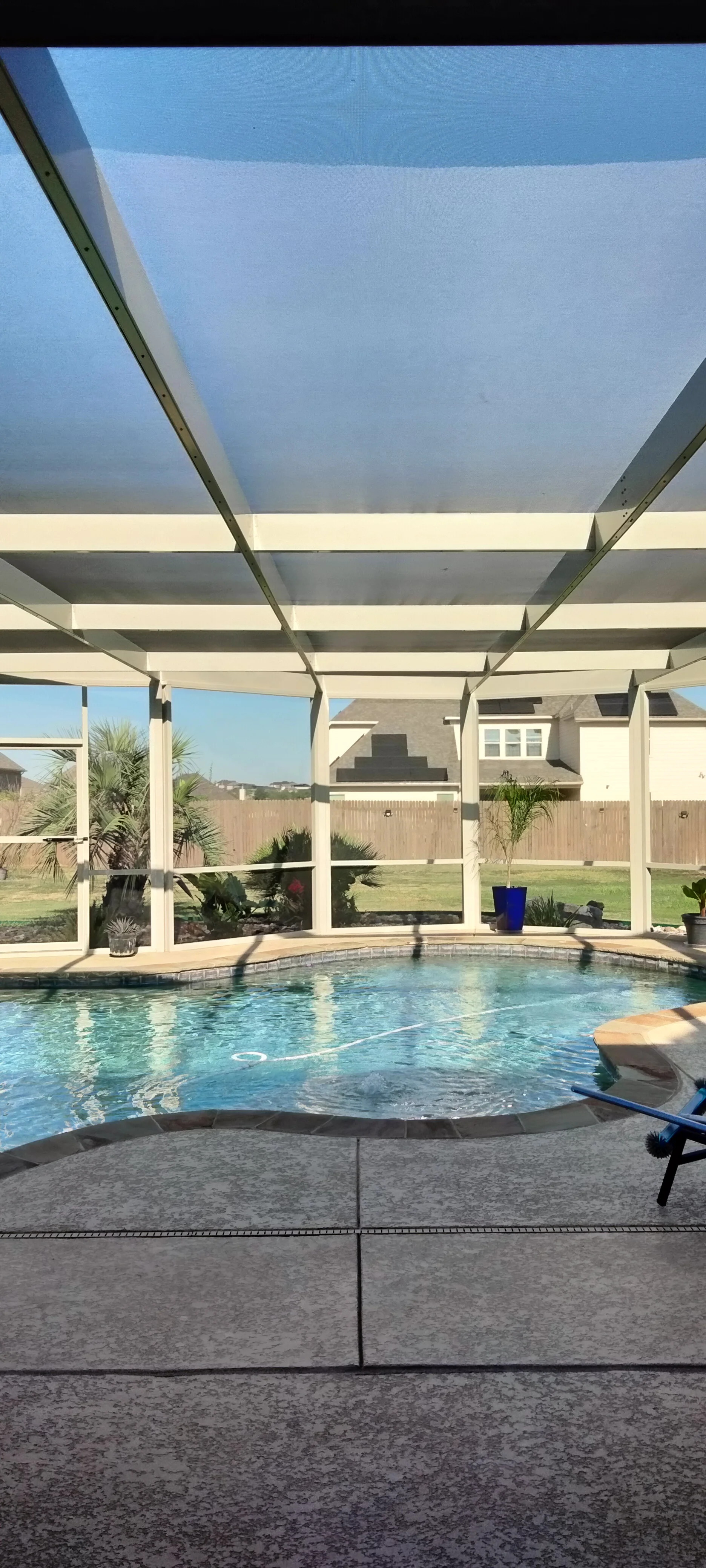 White aluminum screened pool enclosure with retractable shade, glass panels, and paver deck