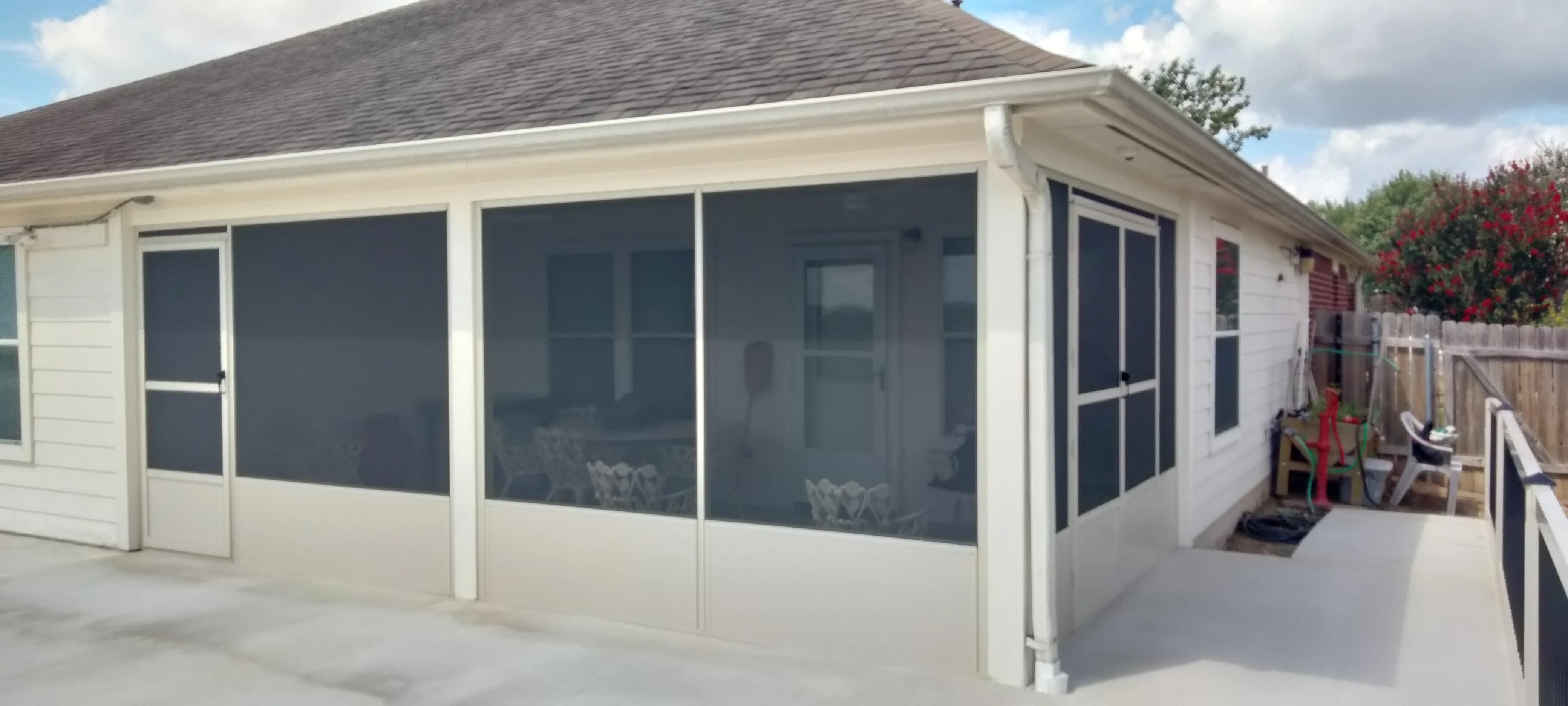 White vinyl patio enclosure with dark mesh screening and solid lower panels