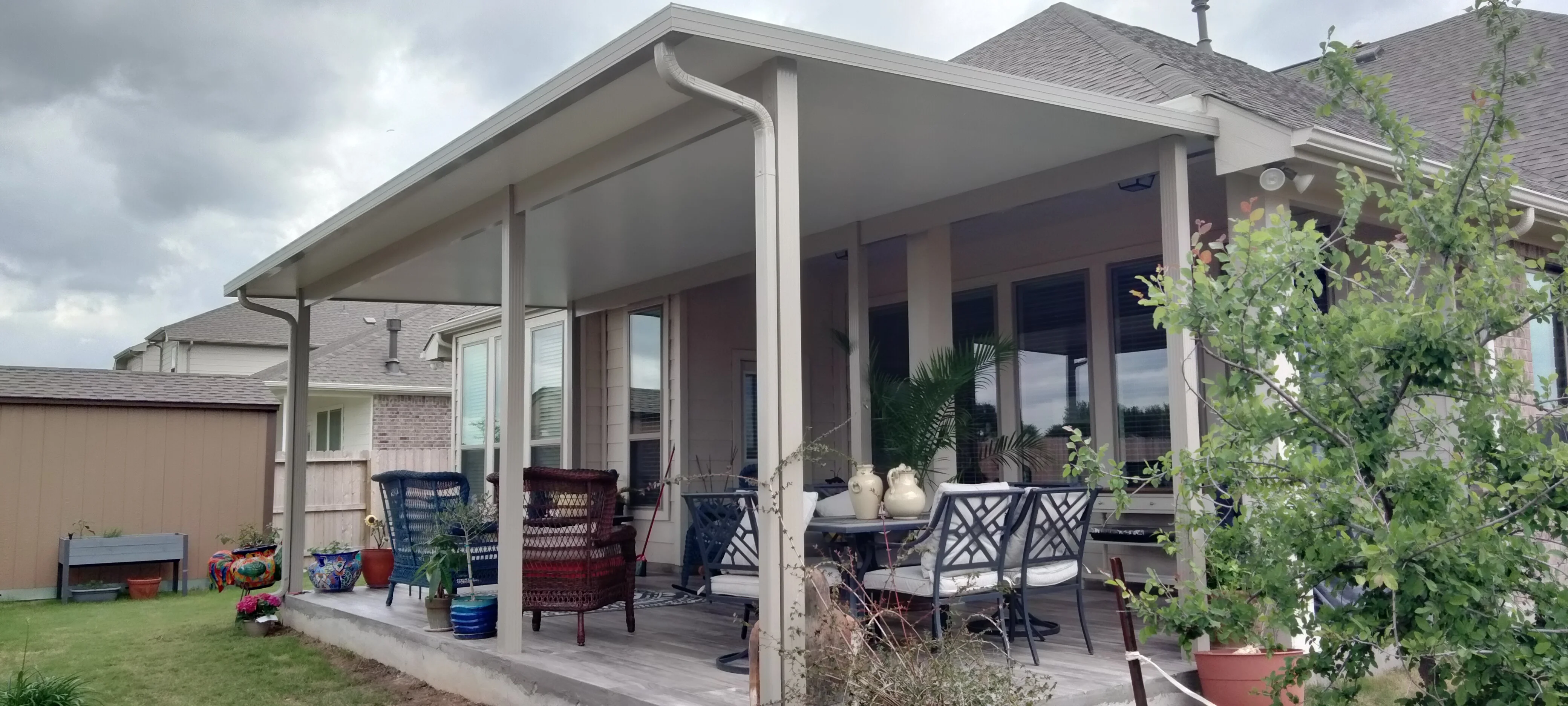 White aluminum patio cover with glass doors, concrete foundation, and integrated seating area