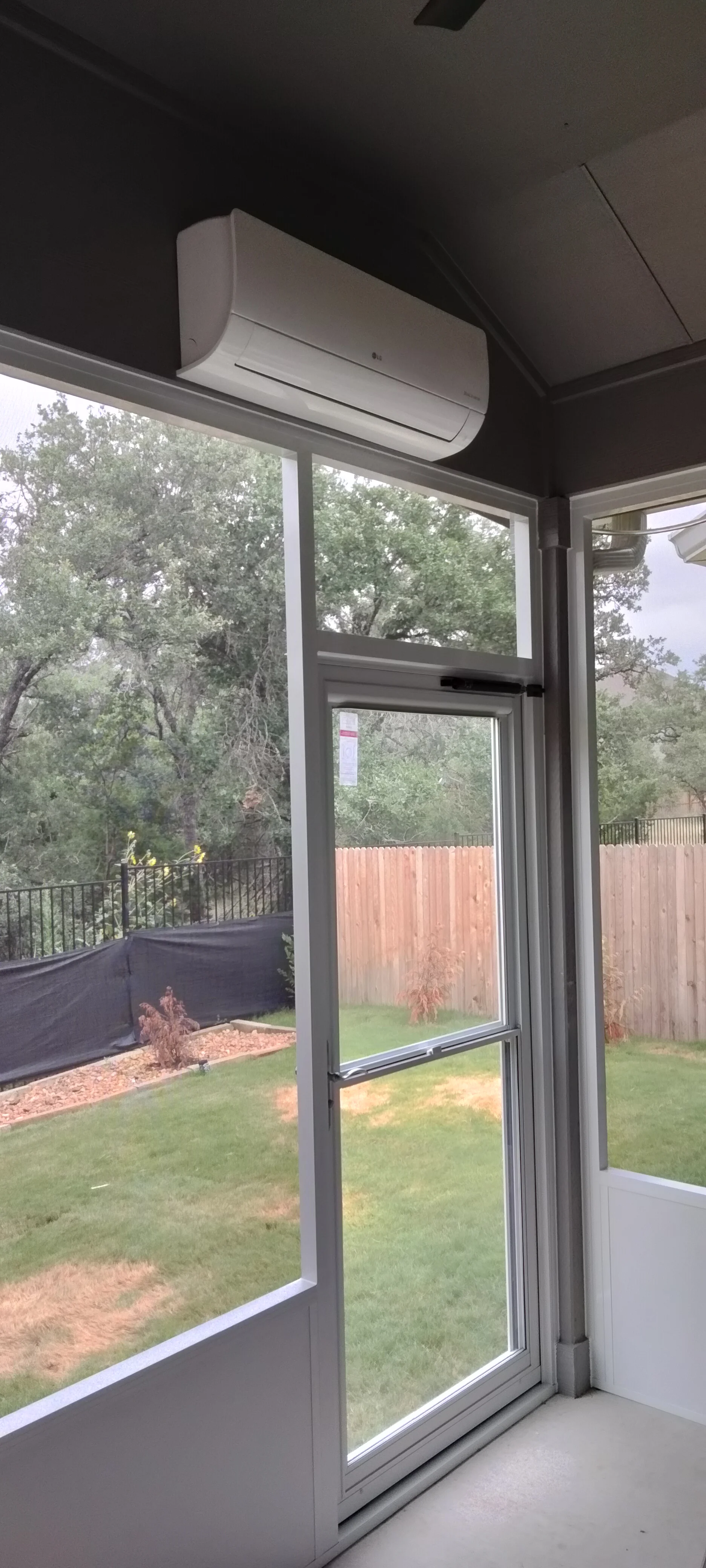 Aluminum patio enclosure with sliding glass doors, fixed windows, and ceiling-mounted AC unit