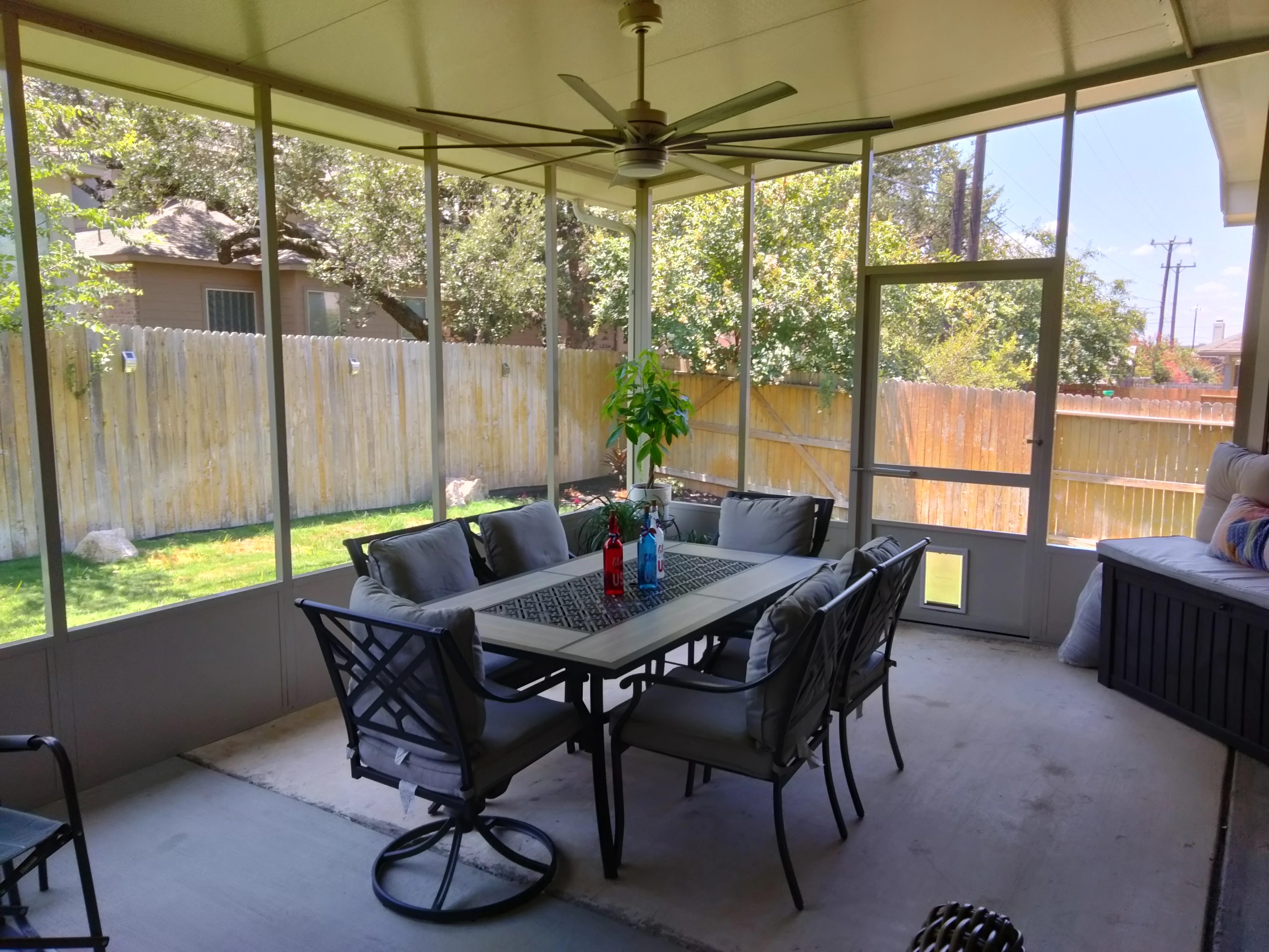 Screened patio with aluminum frame, glass panels, concrete floor, and ceiling fan