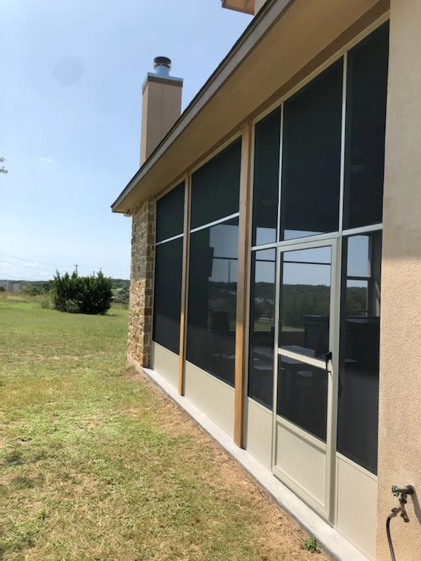 Black screen patio enclosure with aluminum frame and cream knee wall on residential home