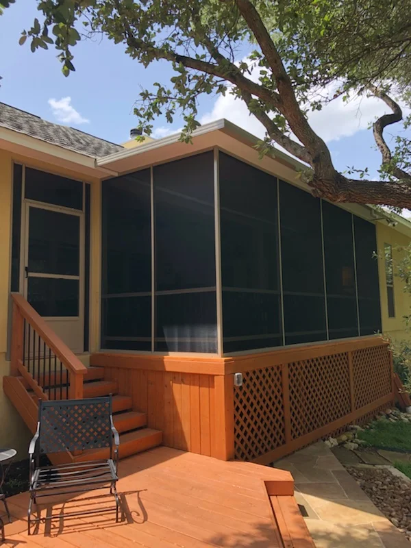 Wood-framed patio enclosure with black screening, composite deck, and lattice skirting