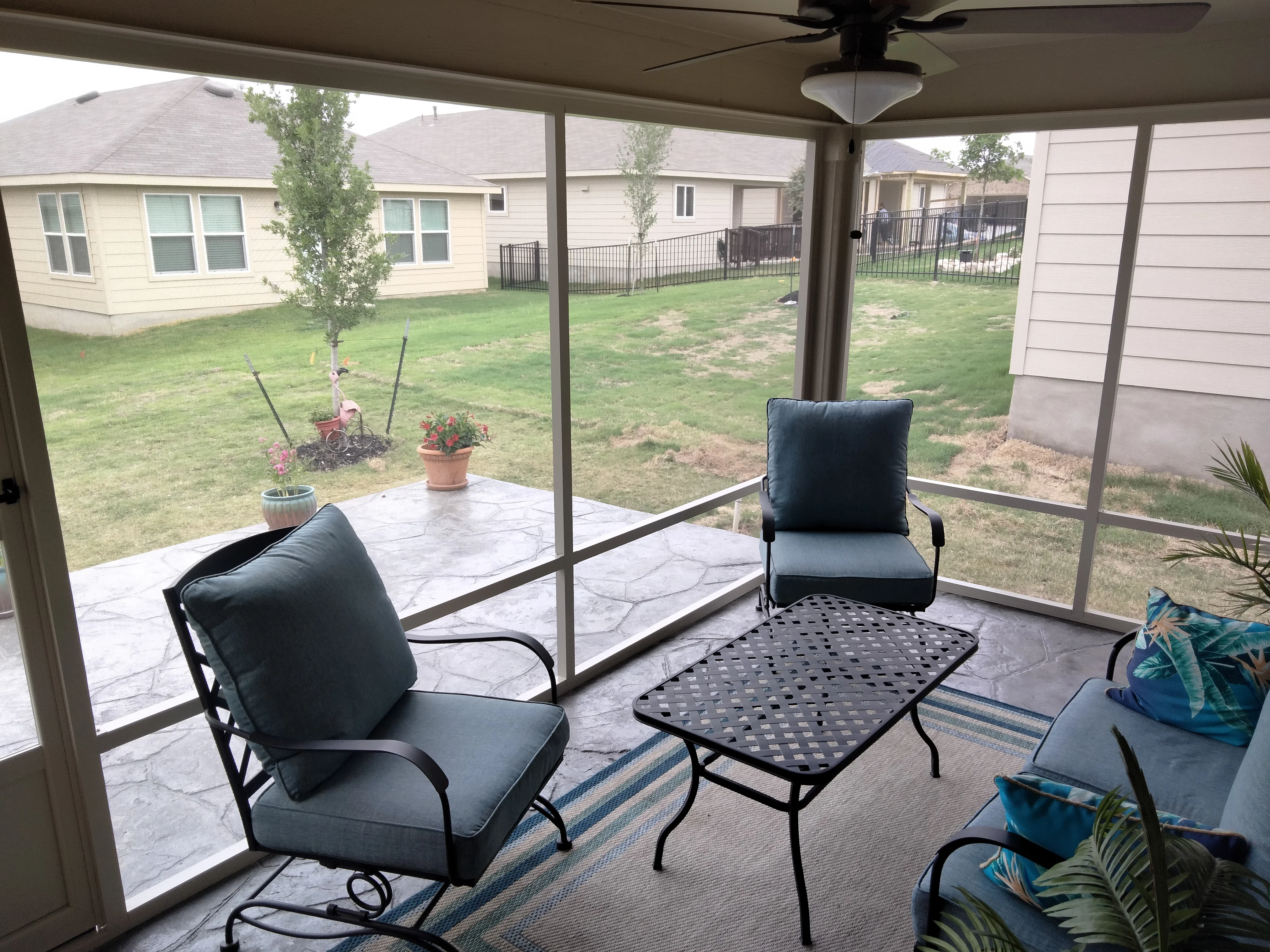 Screened patio with stamped concrete floor, metal furniture, and ceiling fan