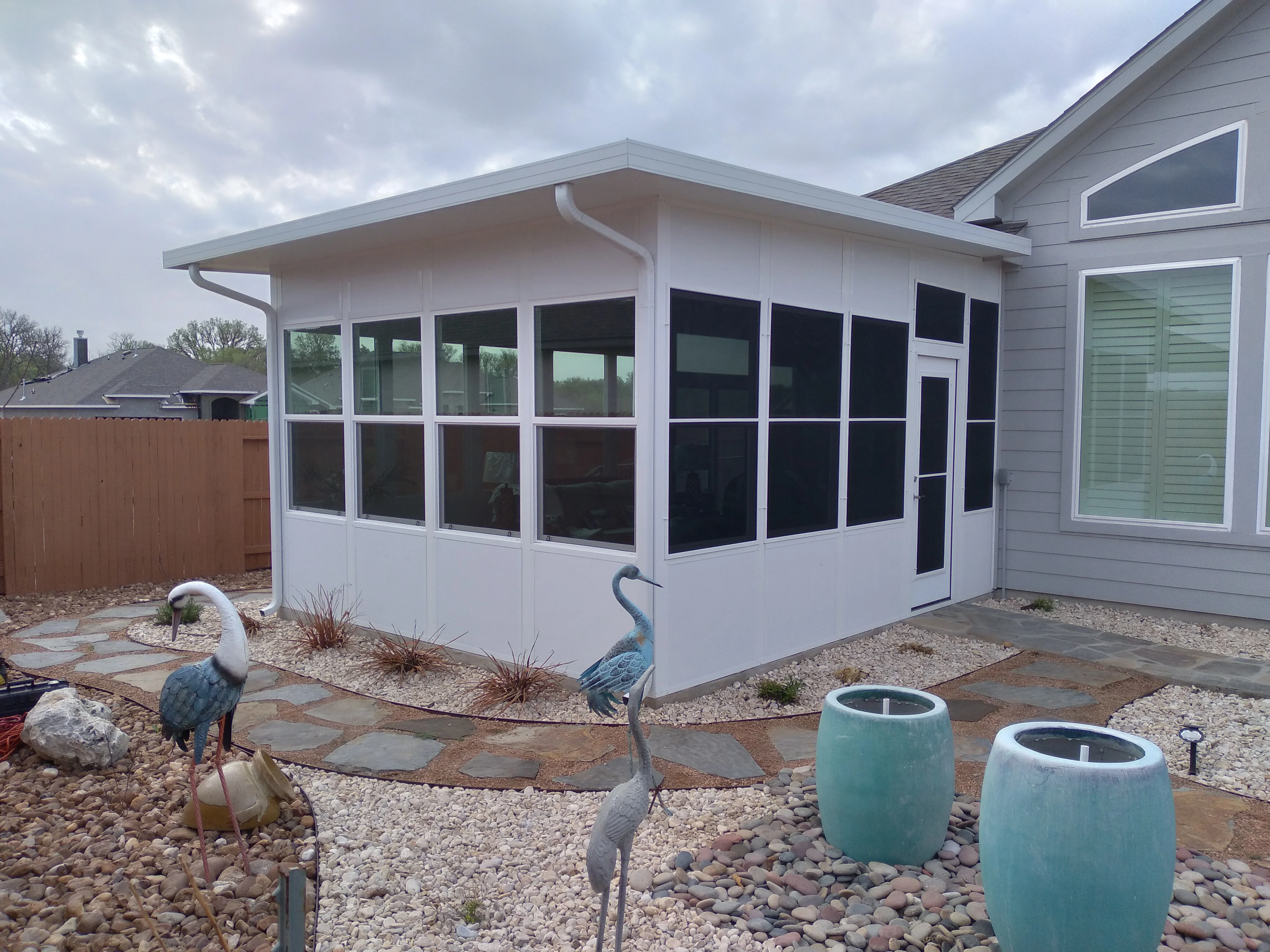 White aluminum patio enclosure with multi-pane windows and sloped roof attached to residential home