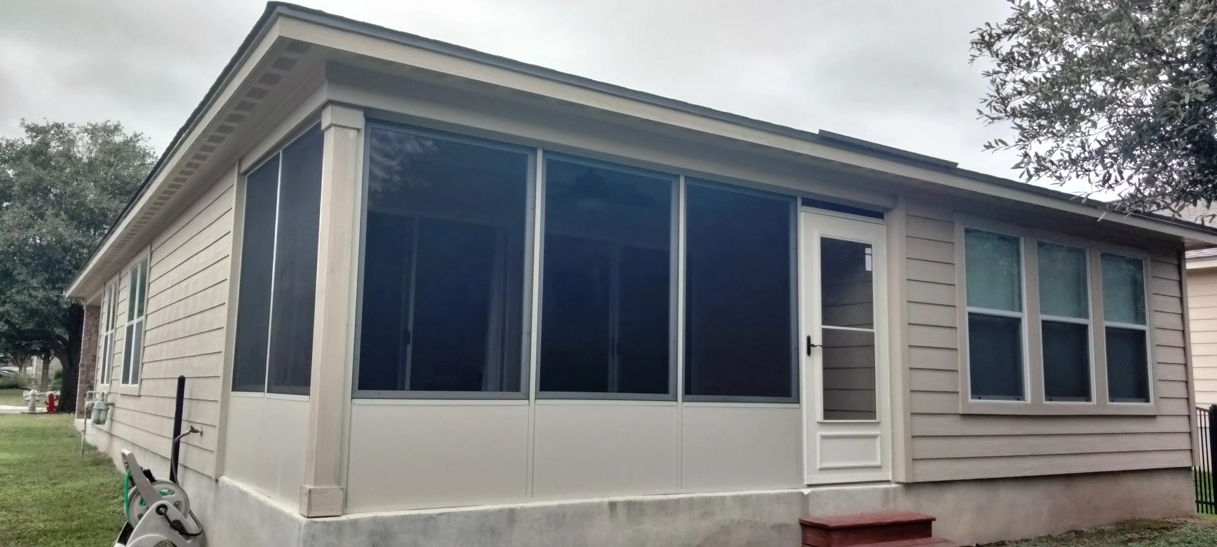Aluminum patio enclosure with tinted vinyl windows, white frame, and matching siding