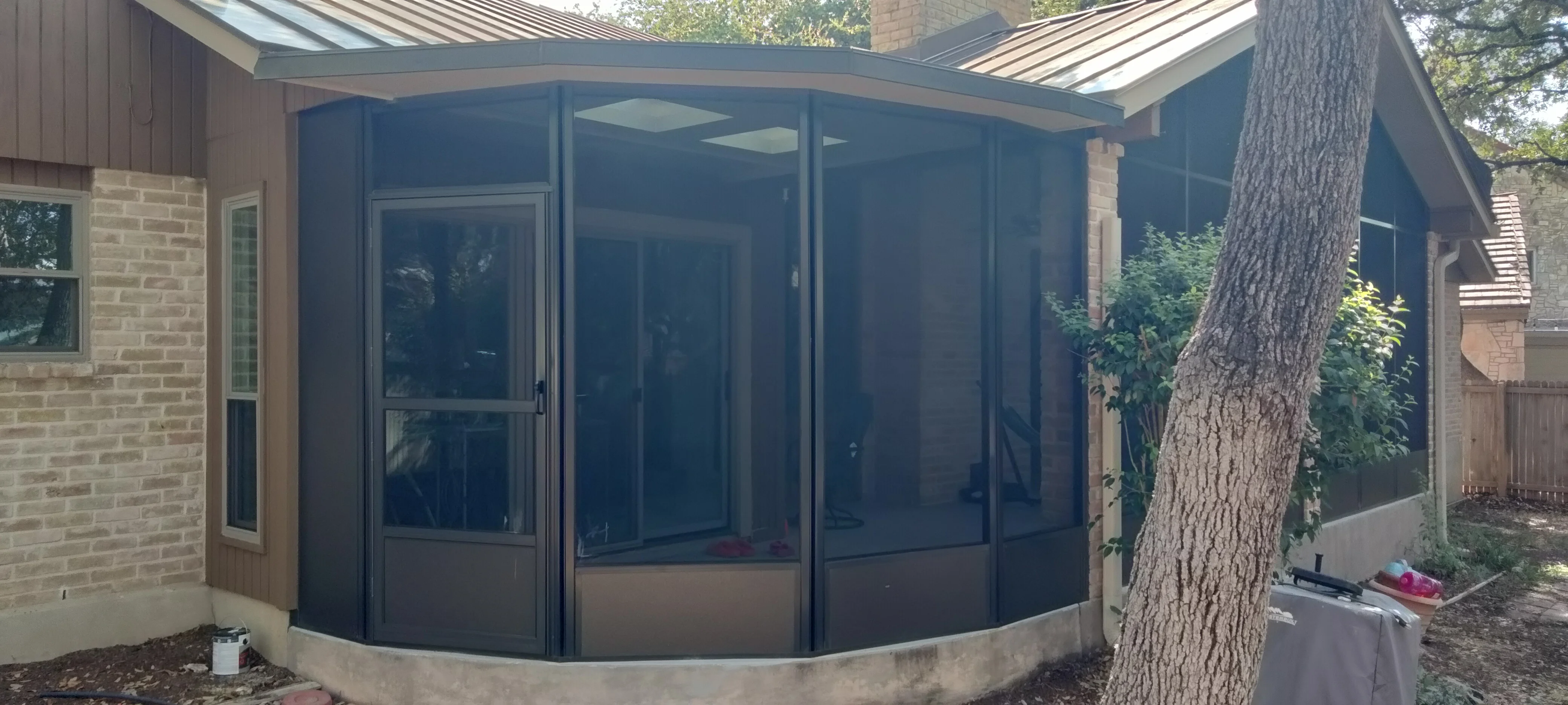 Dark aluminum curved patio screen enclosure with full-height screening panels attached to brick home