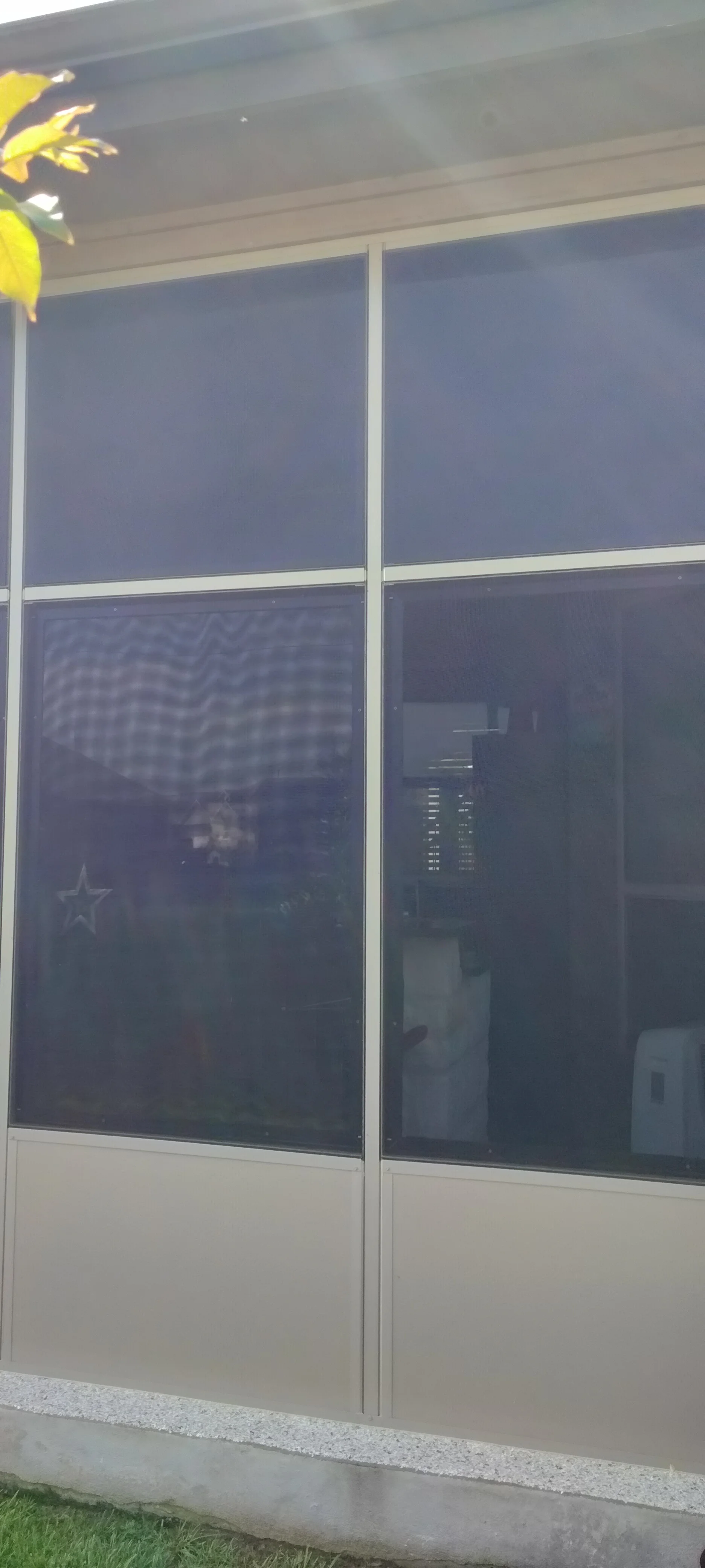 Aluminum patio enclosure with tinted glass panels and tan lower panels