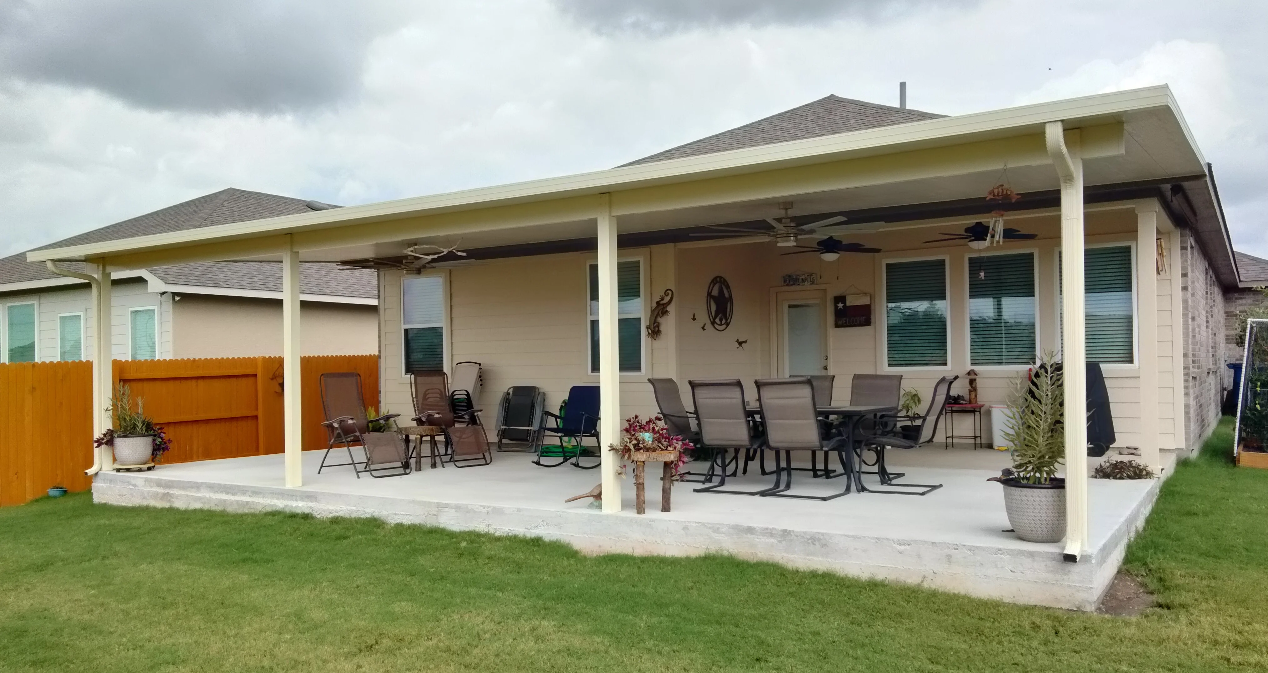 White insulated patio cover with aluminum frame, ceiling fans, and concrete pad foundation