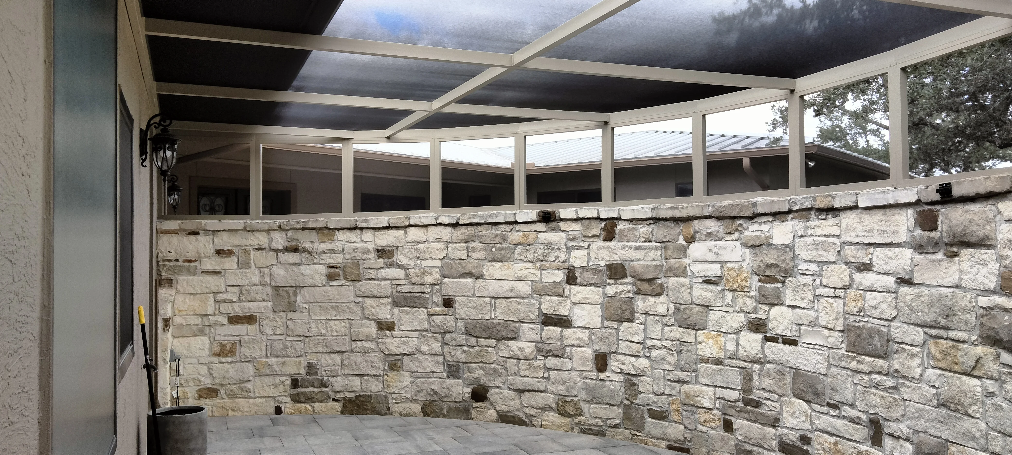 Stacked stone patio wall with aluminum frame and retractable roof panels