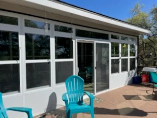 White aluminum frame glass enclosure with sliding doors and fixed panels on composite deck