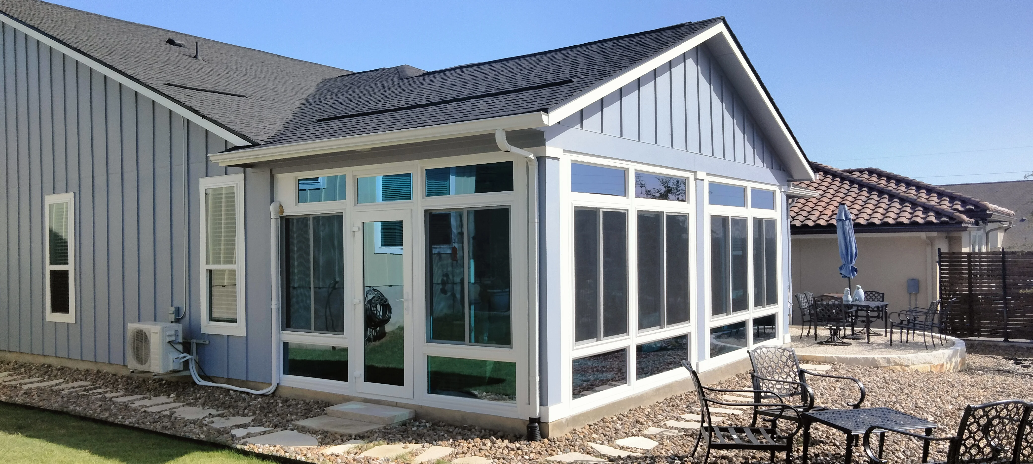 White-framed sunroom with glass panels and screened patio addition to residential home