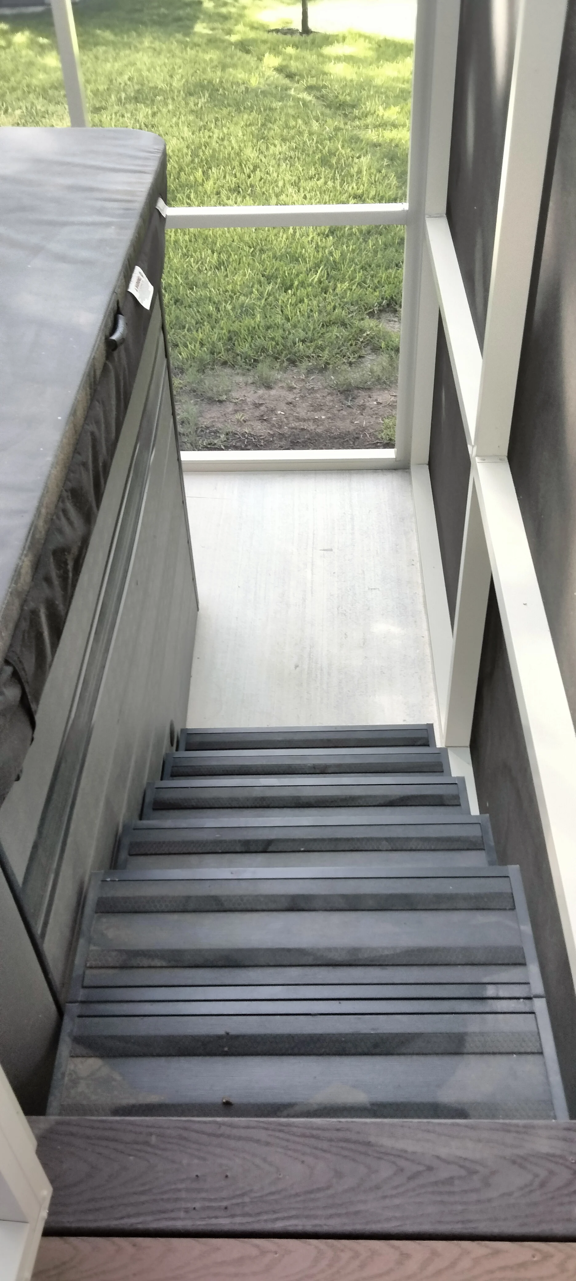 Dark metal stair treads with white-framed glass enclosure overlooking patio area
