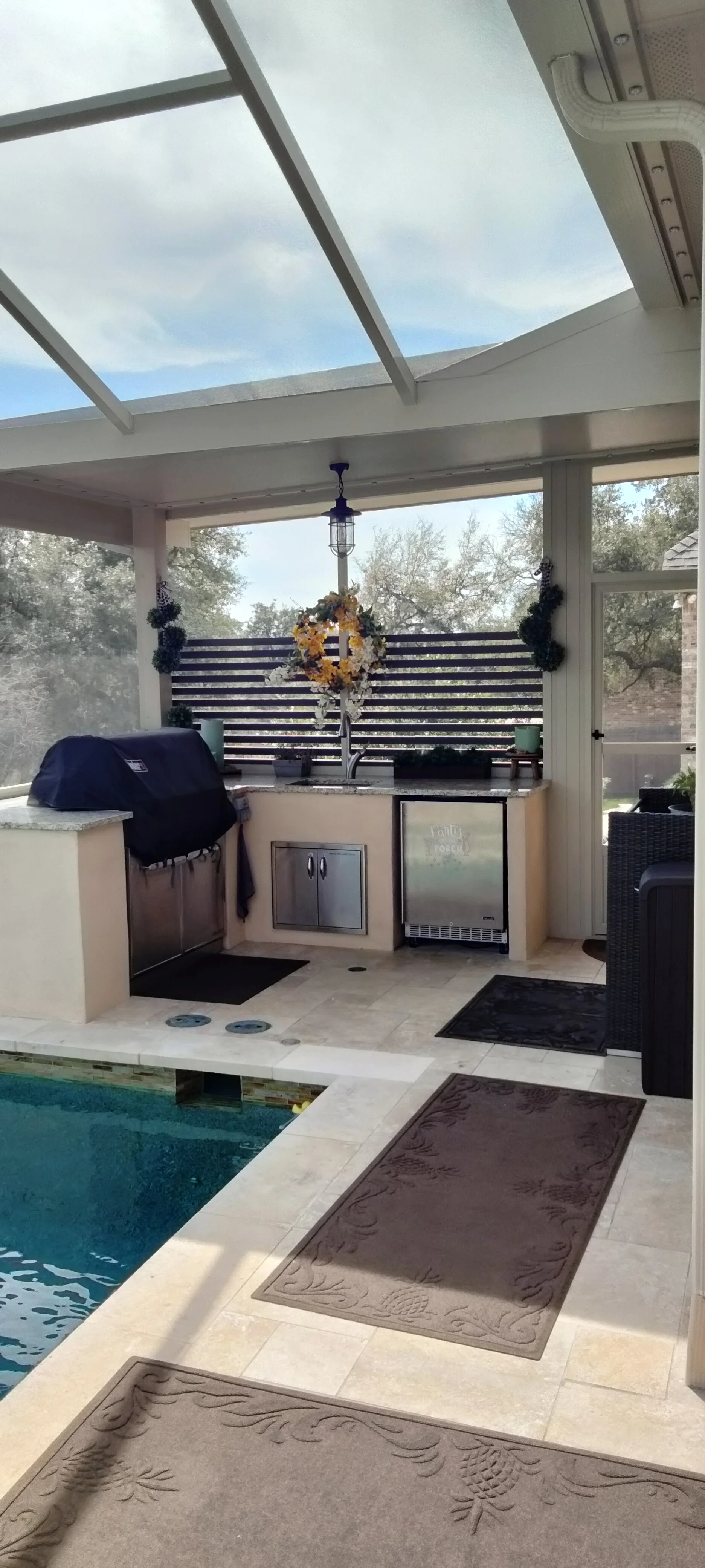 Patio enclosure with polycarbonate roof, outdoor kitchen with grill and refrigerator, travertine flooring
