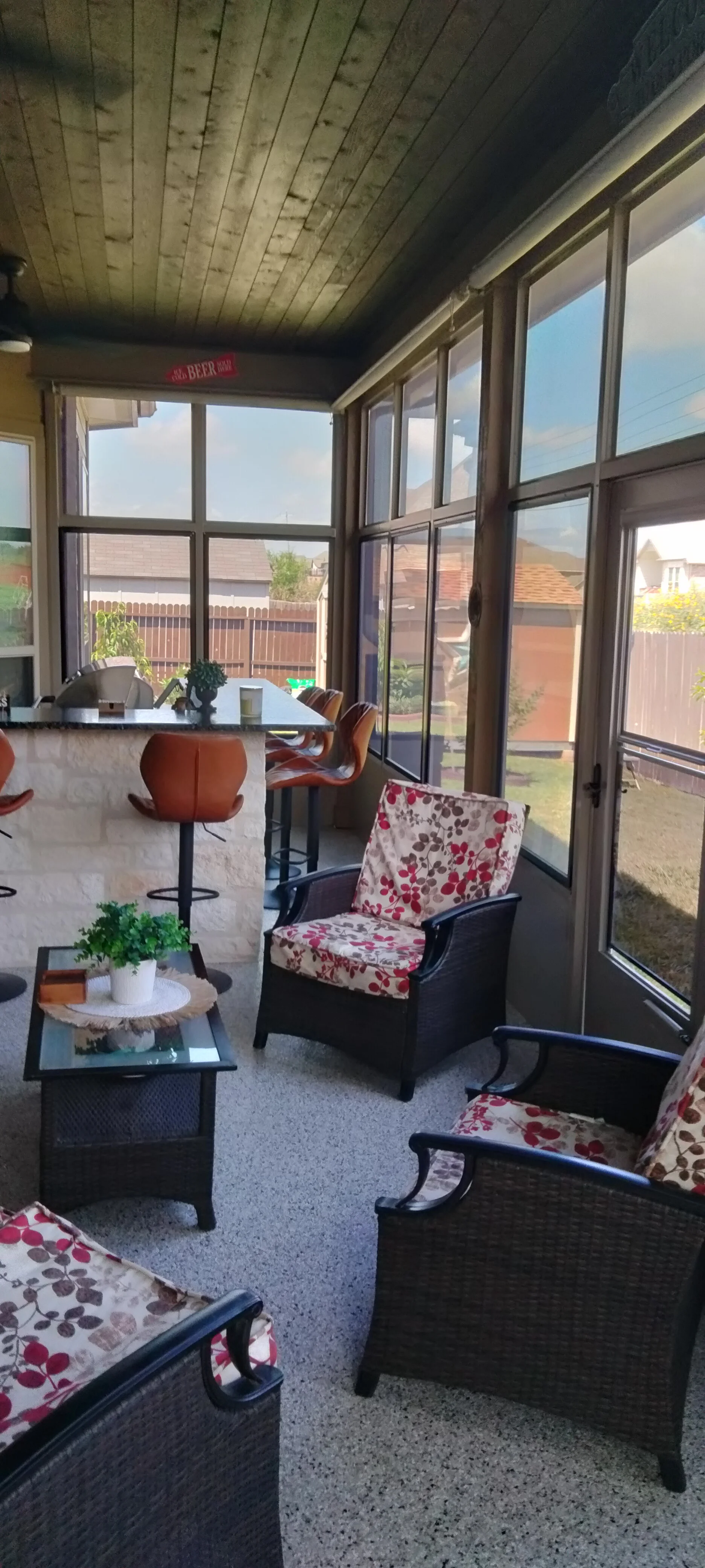 Aluminum frame sunroom with glass panels, concrete floor, and wooden ceiling