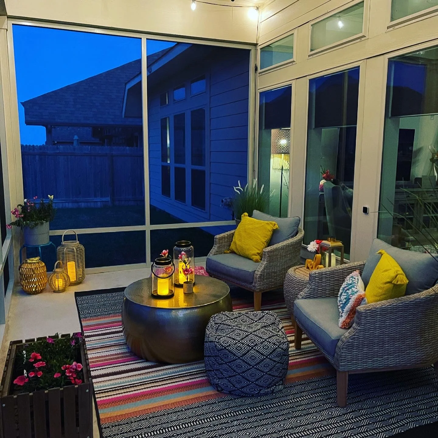 Screened patio enclosure with aluminum frame, glass panels, wicker seating, and recessed lighting