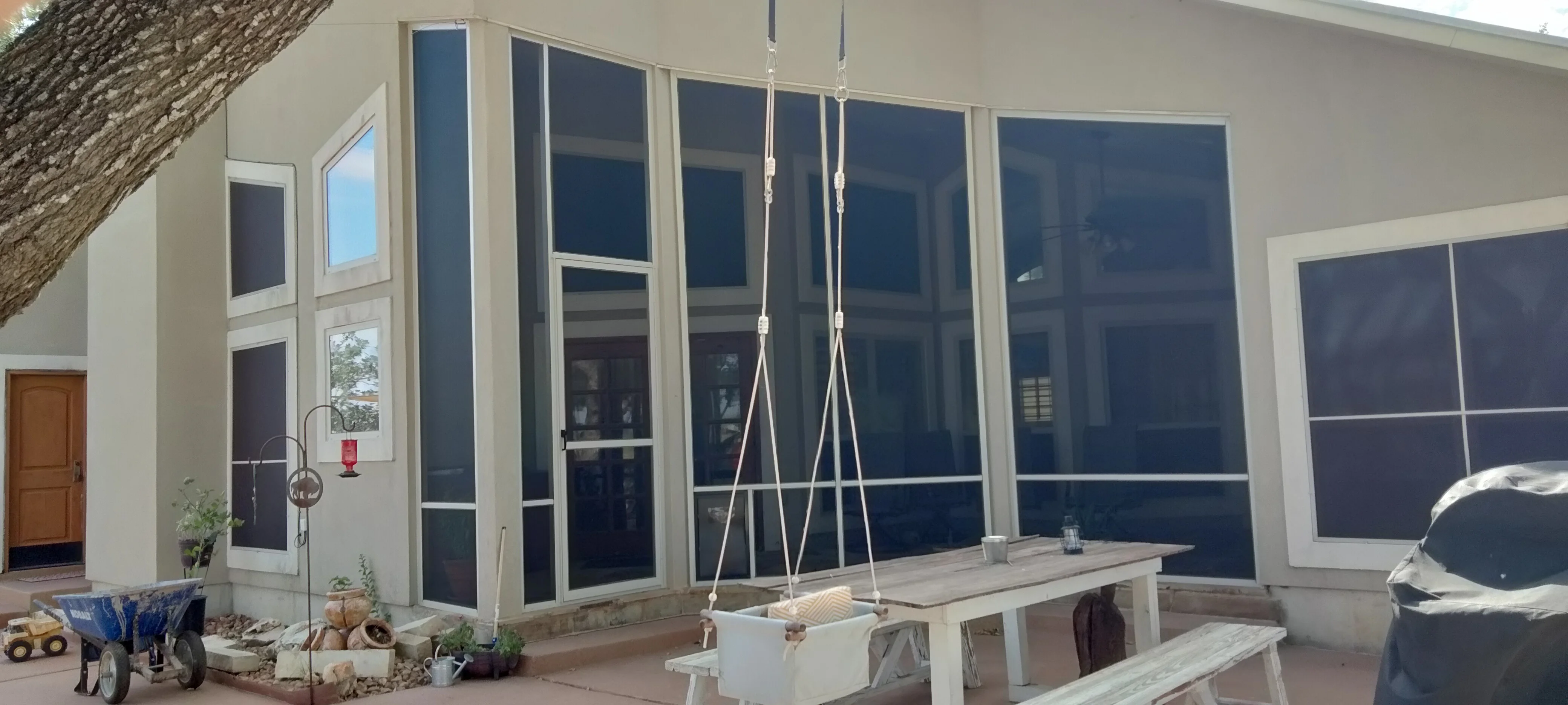 Motorized retractable screens with white aluminum frames and dark mesh panels on patio enclosure