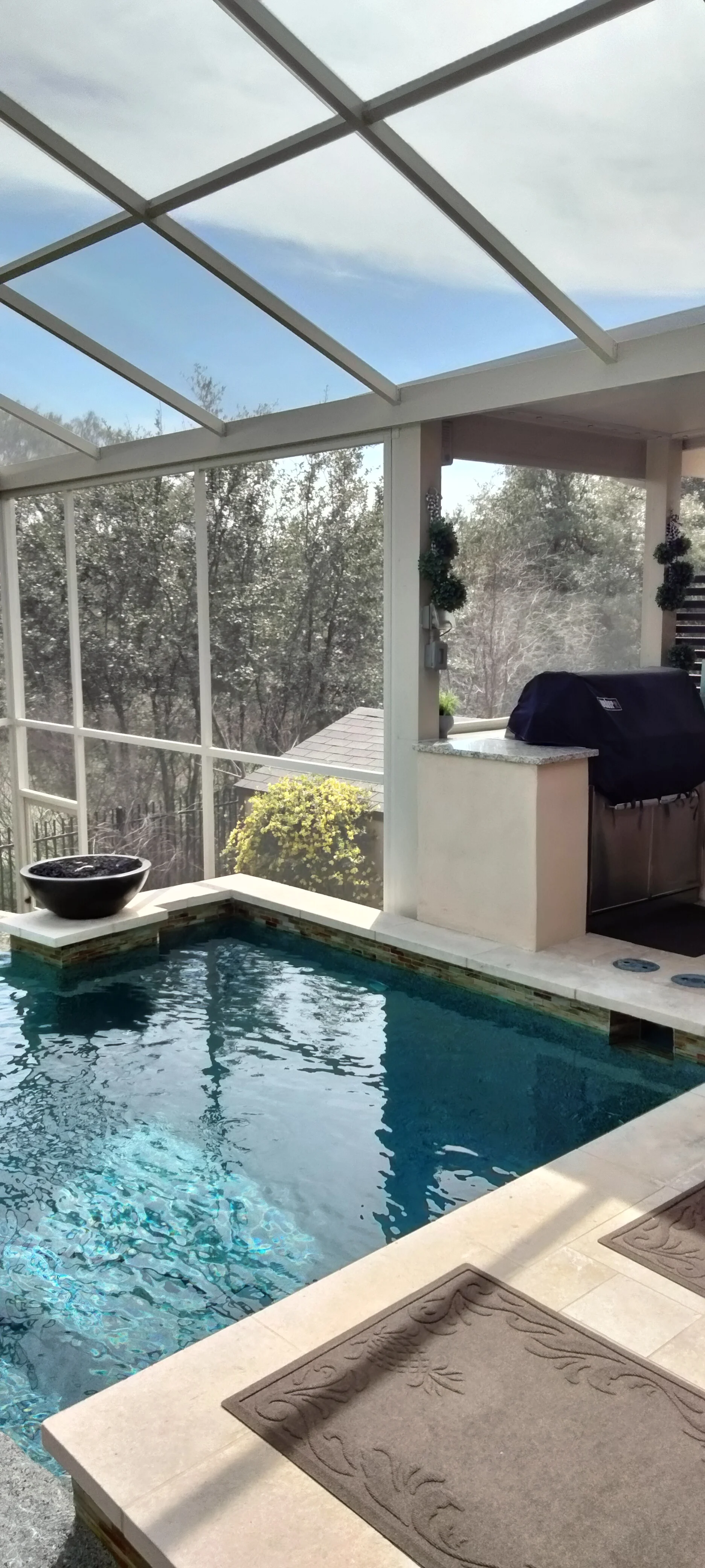Glass roof patio enclosure over indoor pool with aluminum frame and full-height windows