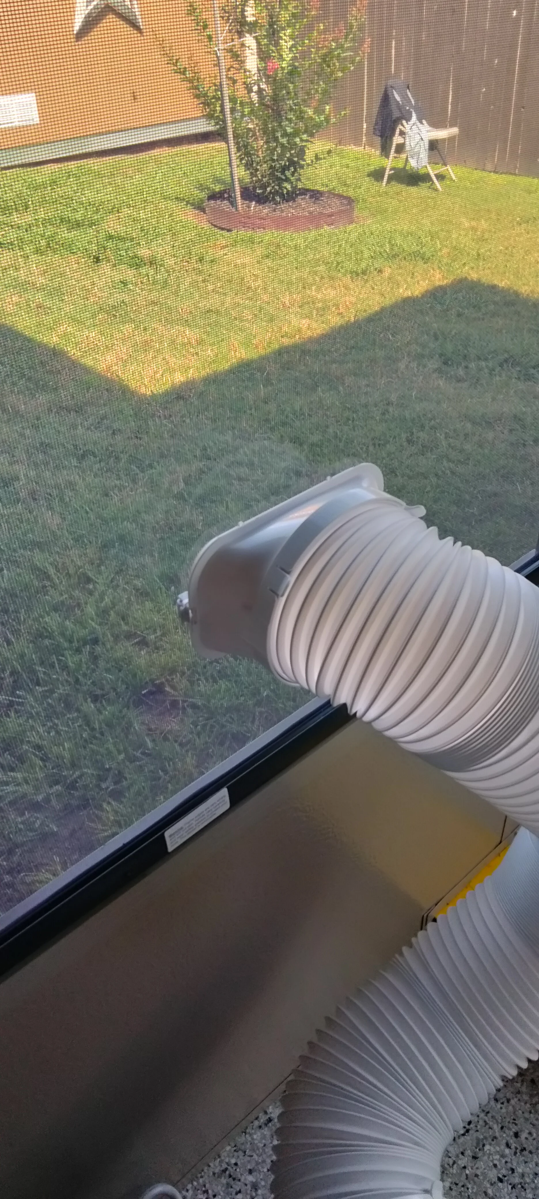 White vinyl ducting and black aluminum frame patio enclosure over lawn with mesh screening