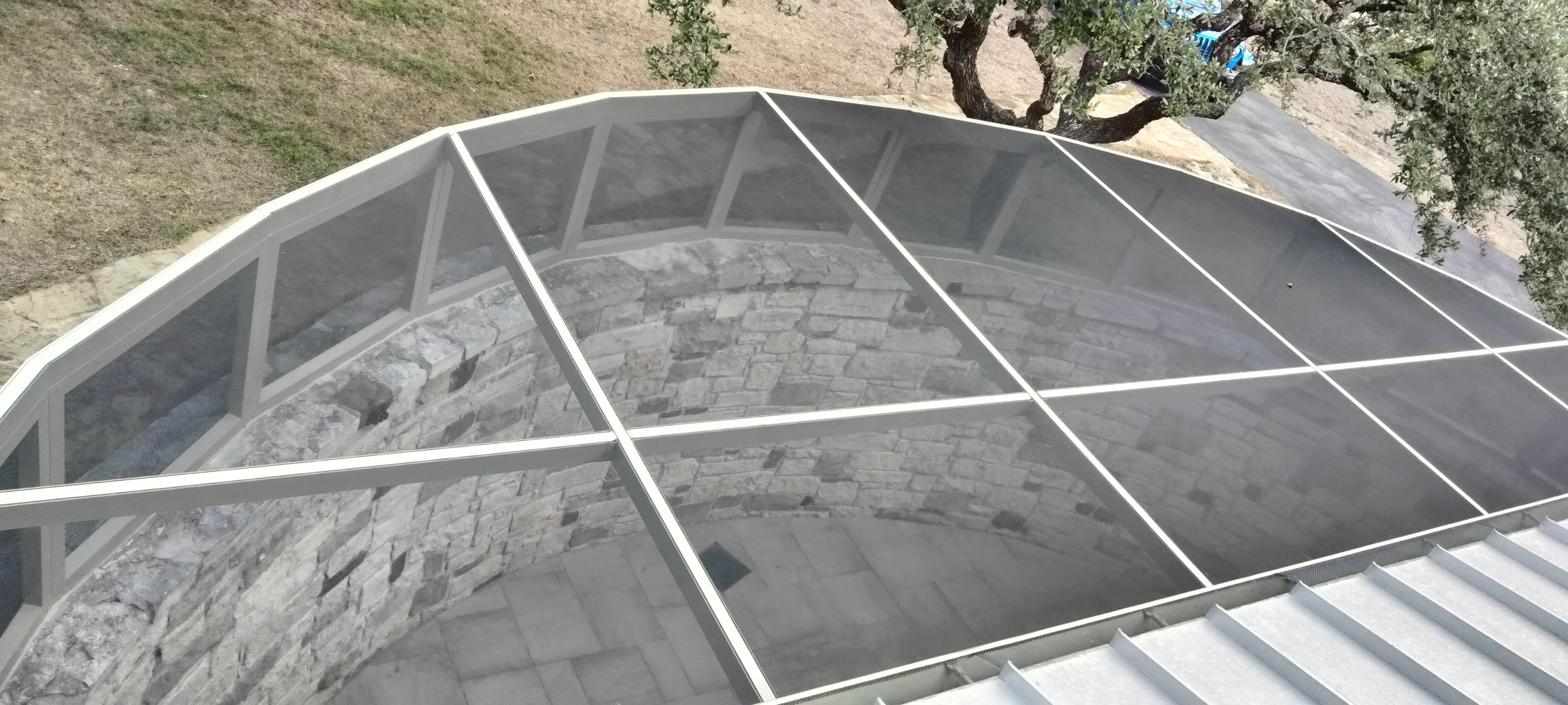 Aluminum patio enclosure with glass panels and stone veneer wall detail