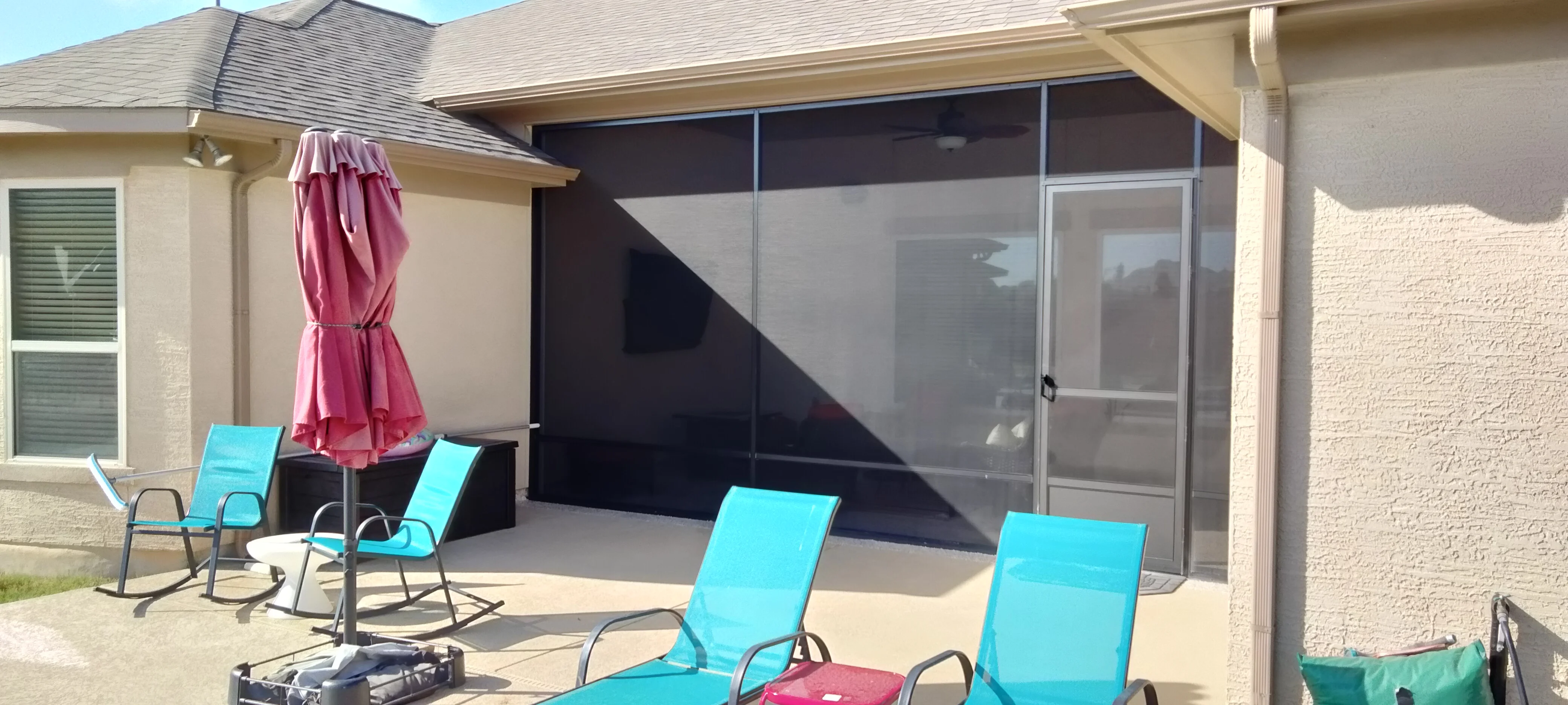 Retractable black mesh screen enclosure on patio with stone home exterior