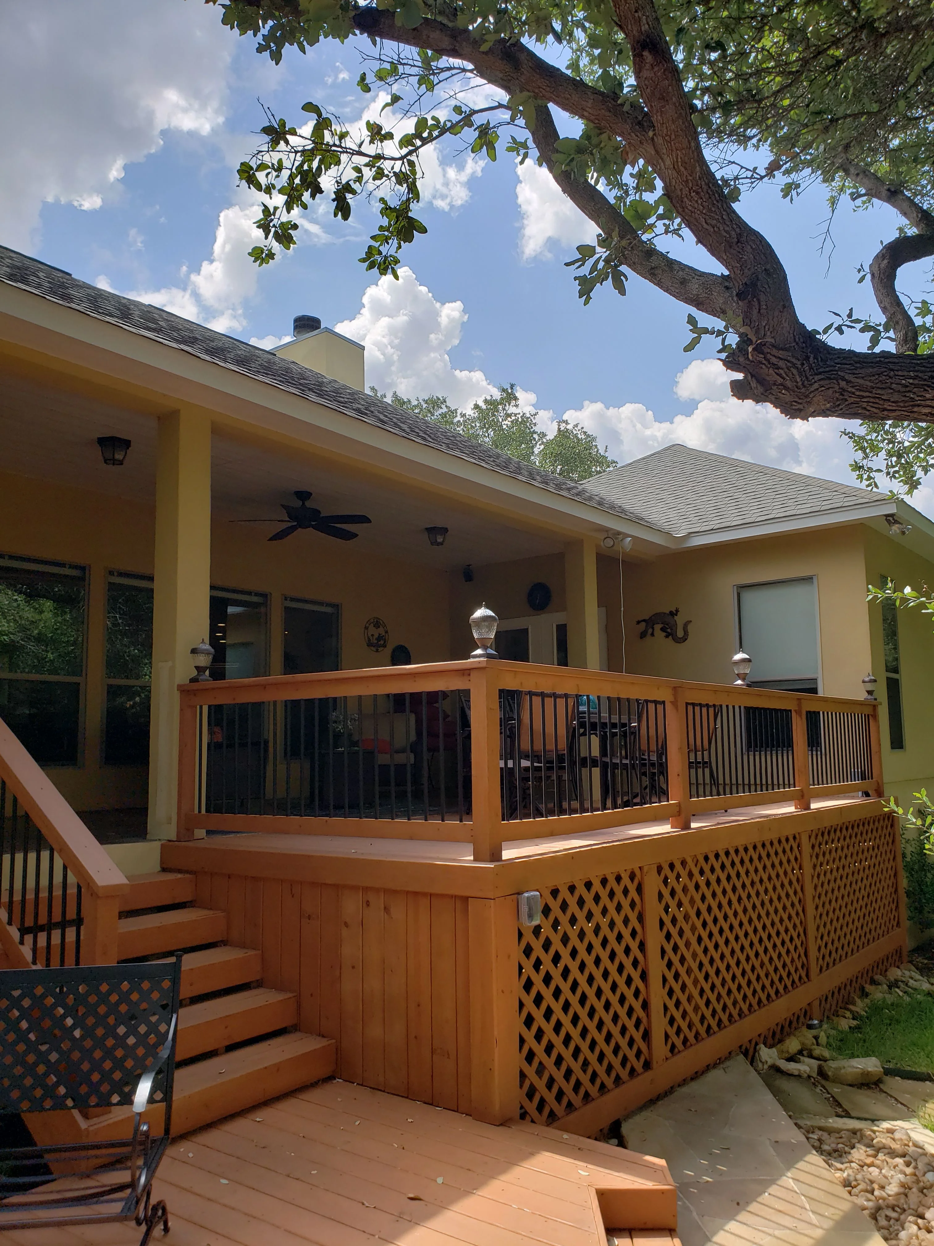 Cedar deck with black metal railings, lattice skirting, and insulated patio cover with gable roof