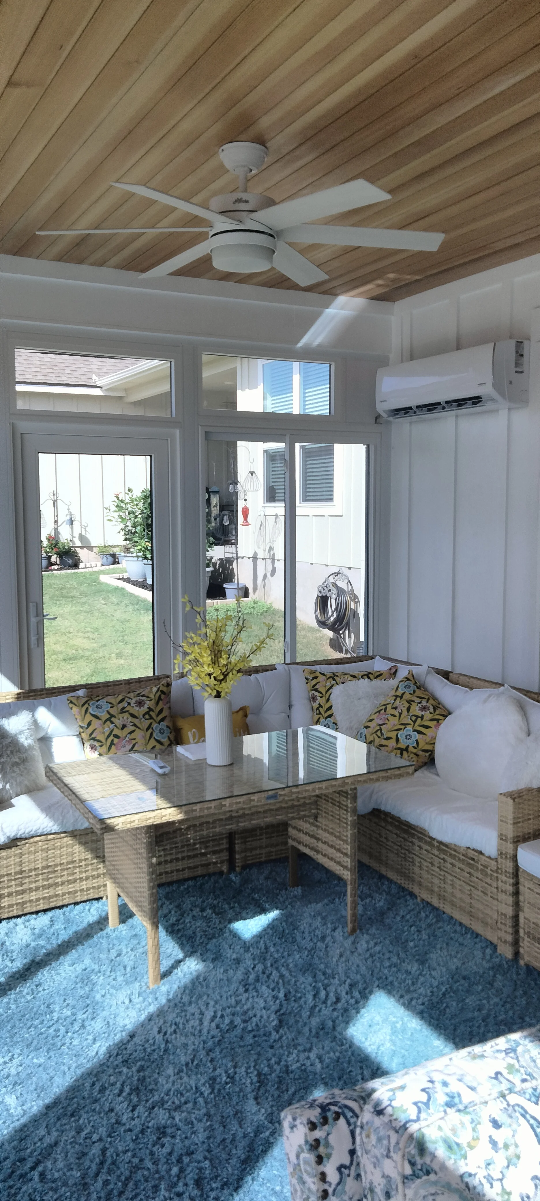 Sunroom interior with wood vaulted ceiling, ceiling fan, glass doors, and AC unit