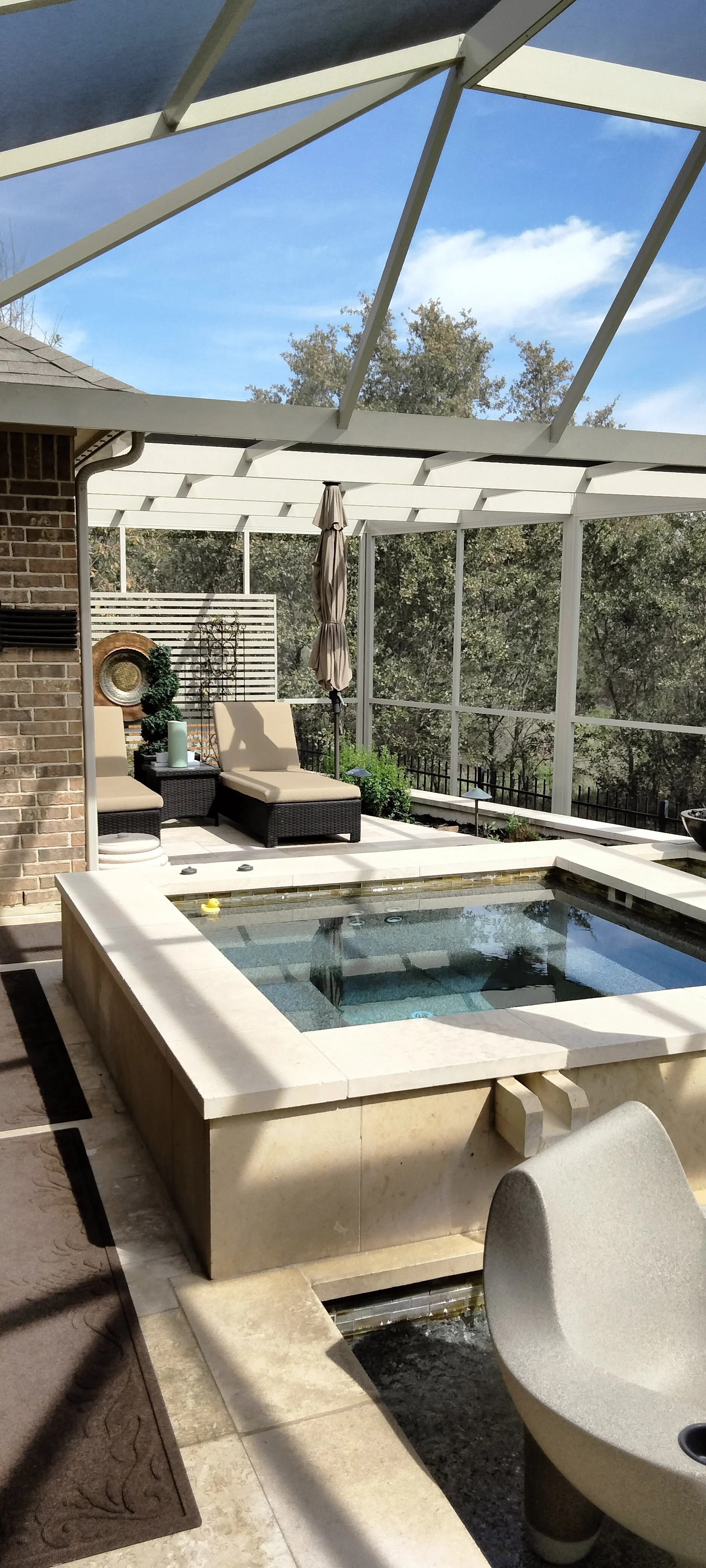 Louvered aluminum patio enclosure with integrated spa, screening, and lounge seating
