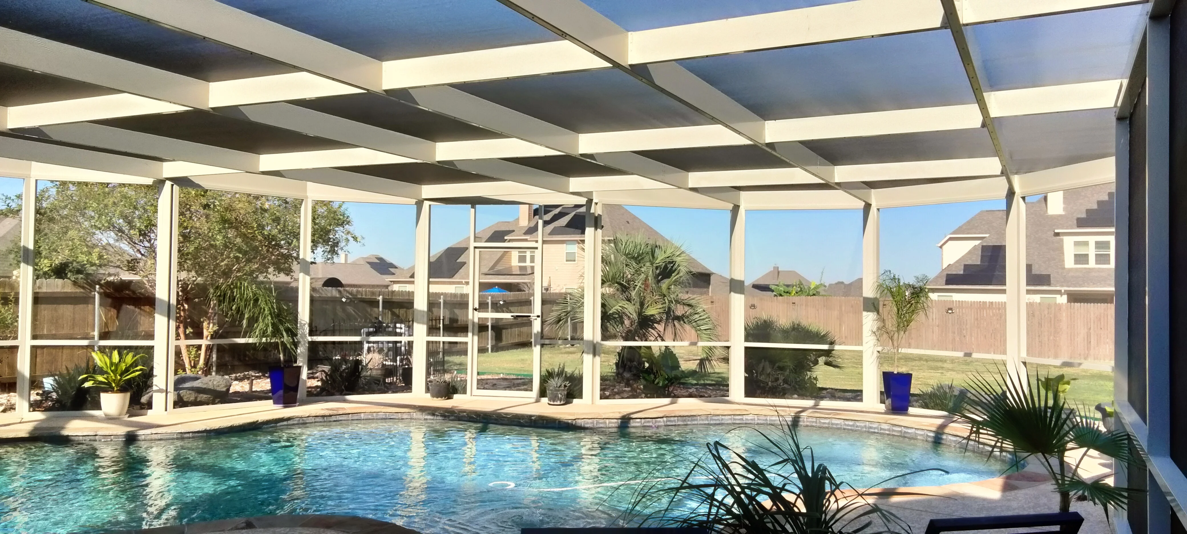 Motorized retractable louver patio enclosure with glass panels over pool area