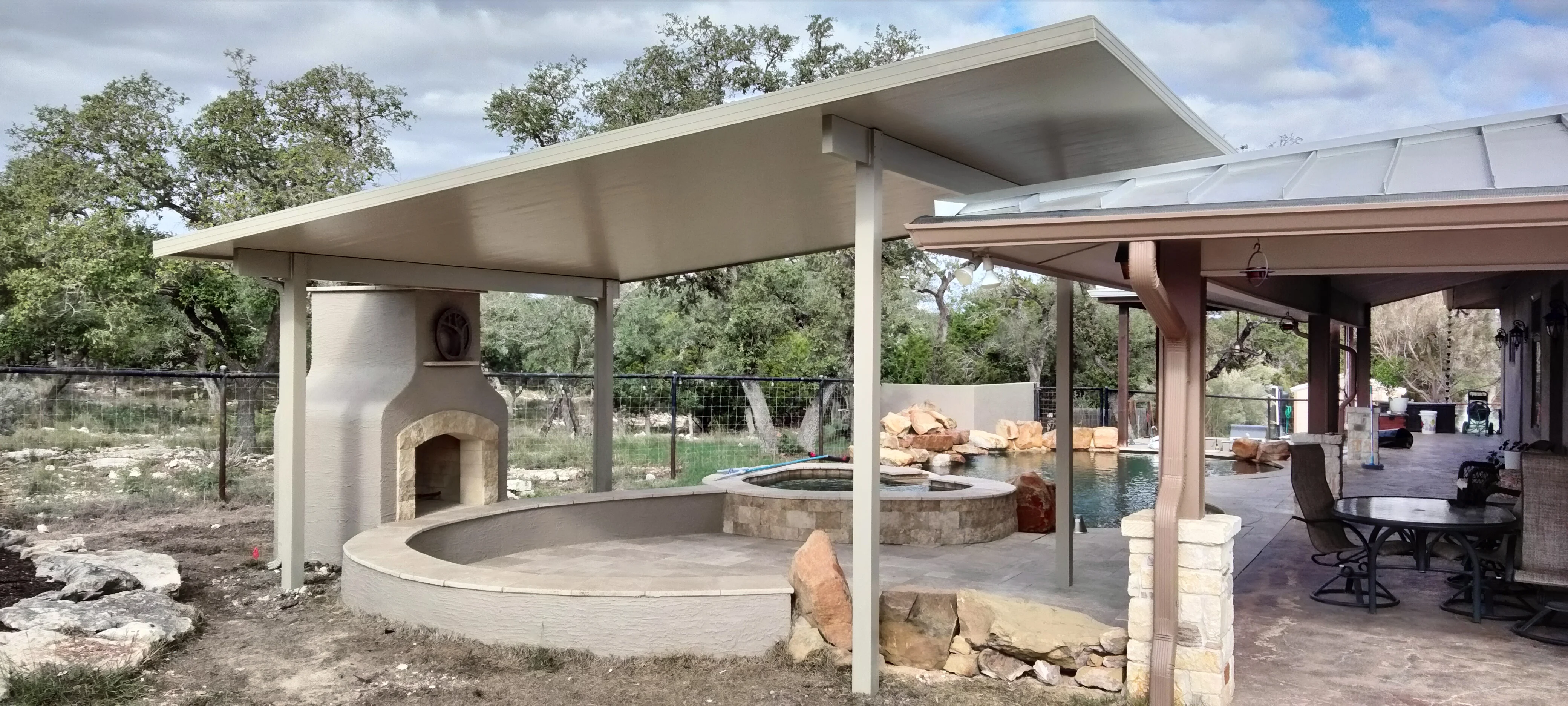 Modern patio with white steel pergola, concrete fire pit, and stucco pizza oven