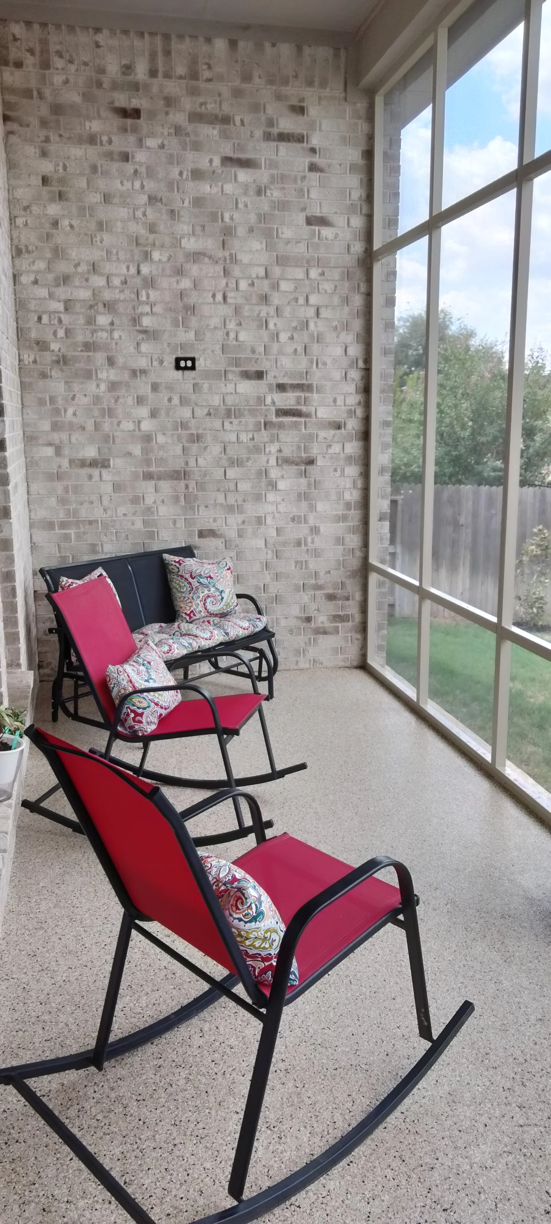 Brick patio enclosure with aluminum-framed windows and concrete flooring