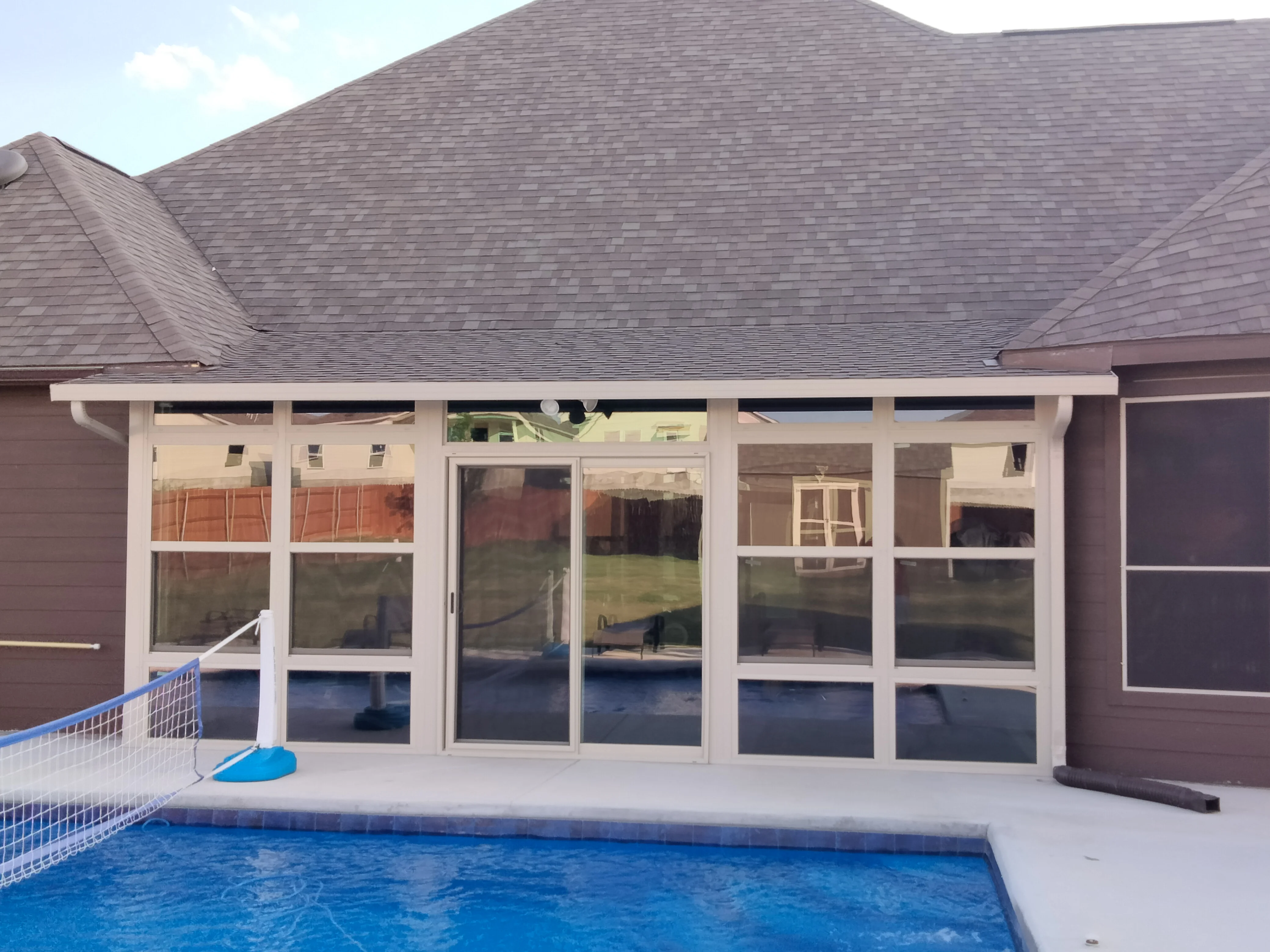 White aluminum patio enclosure with glass panels overlooking swimming pool